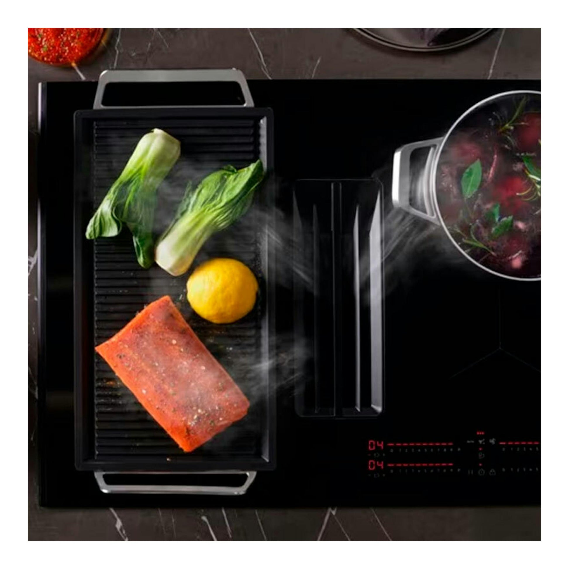 Placa de inducción AEG TCH74B01FB negra, vista superior, con extractor integrado y alimentos cocinándose.
