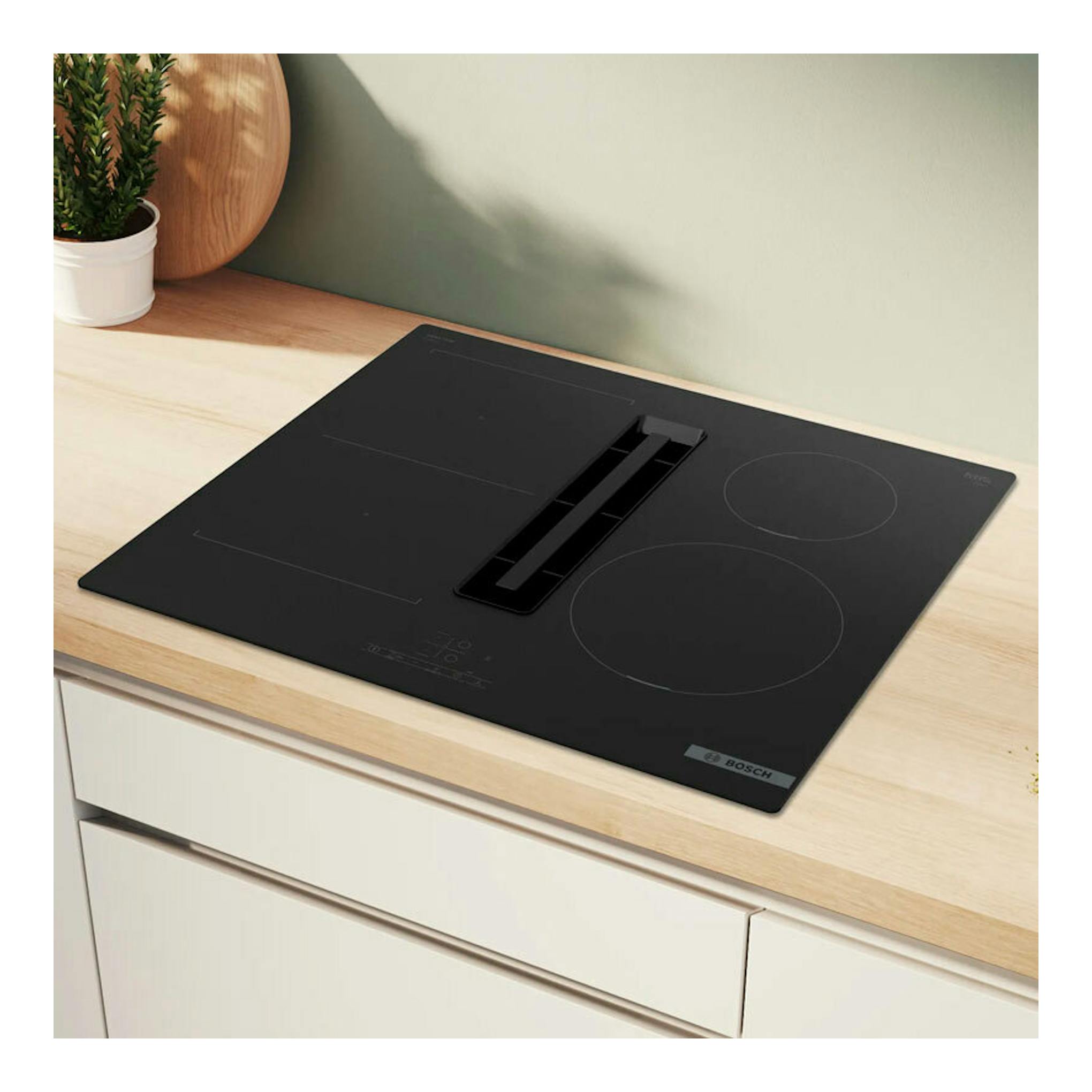 Placa de inducción Bosch PVS611B16E negra con extractor integrado, vista superior sobre encimera de madera.