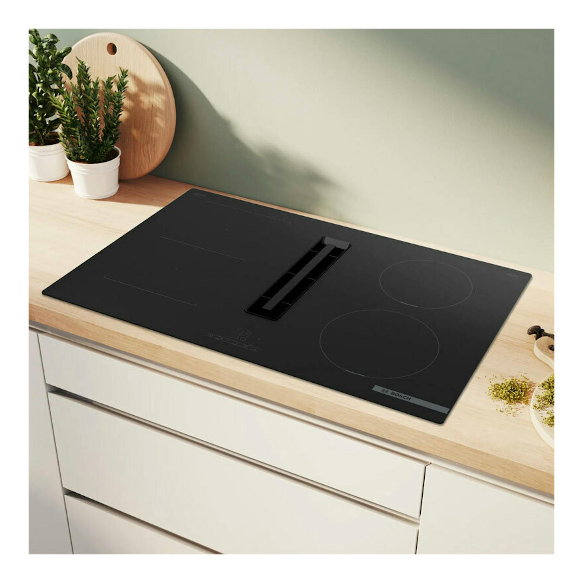 Placa de inducción Bosch PVS811B16E negra con extractor integrado, vista en ángulo sobre encimera clara.