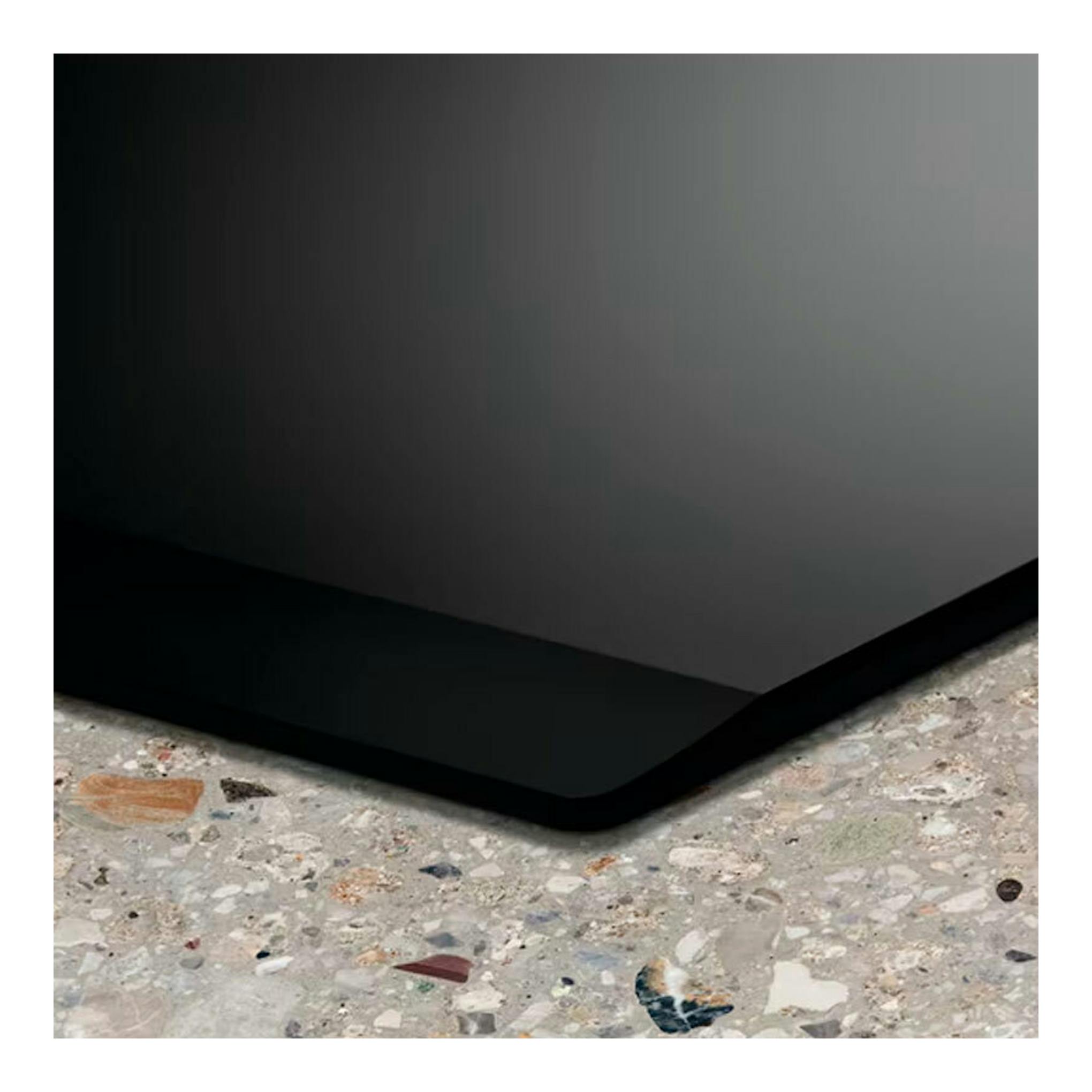 Placa de inducción Electrolux EIV644 negra, vista parcial en primer plano de la esquina sobre encimera.