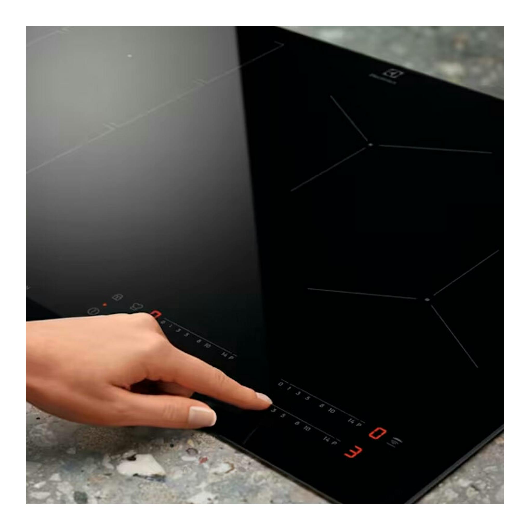 Placa de inducción Electrolux EIV644 negra, vista en ángulo con controles táctiles y una mano operándola.
