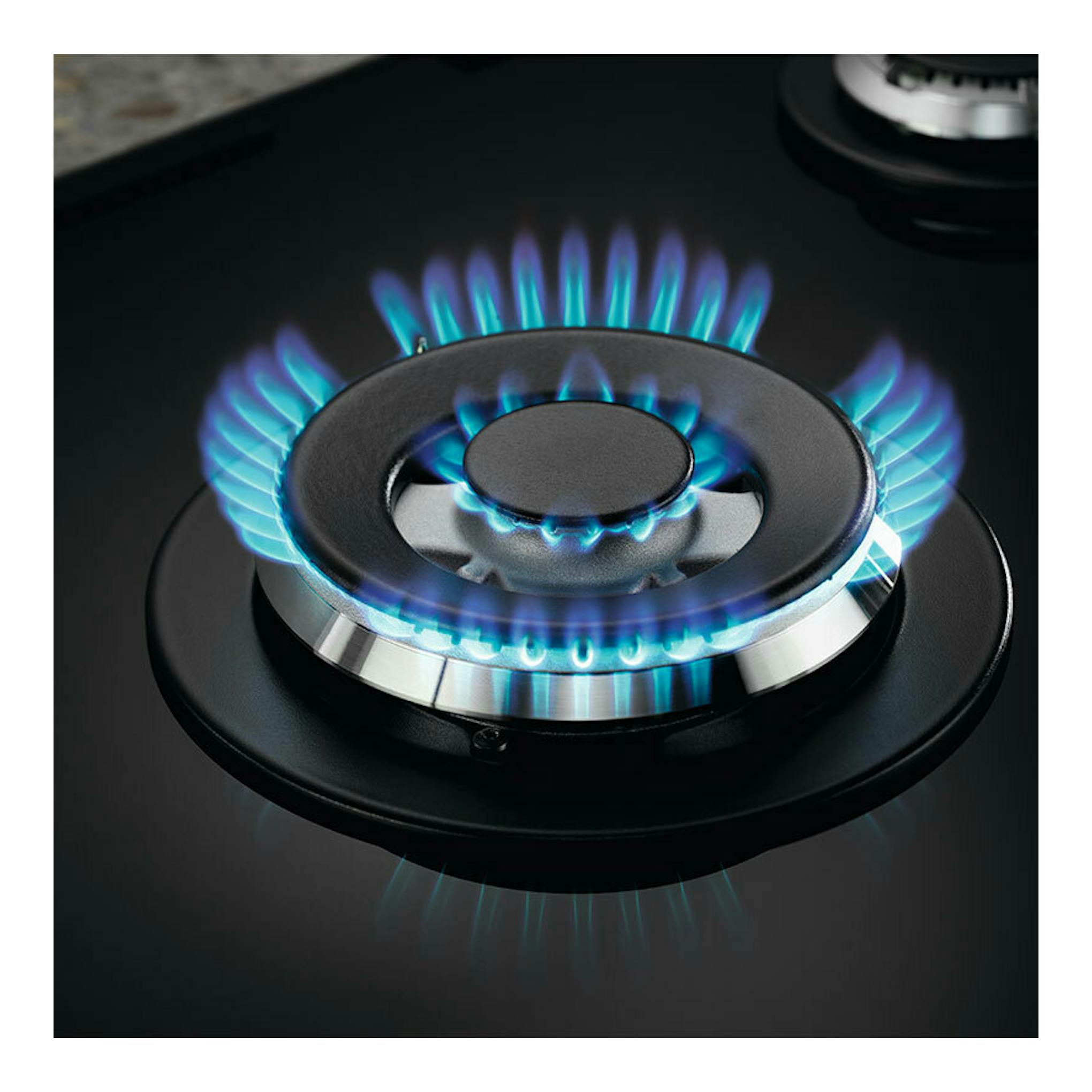 Primer plano de un quemador de placa de gas Electrolux KGG75362K en negro, con llama azul.