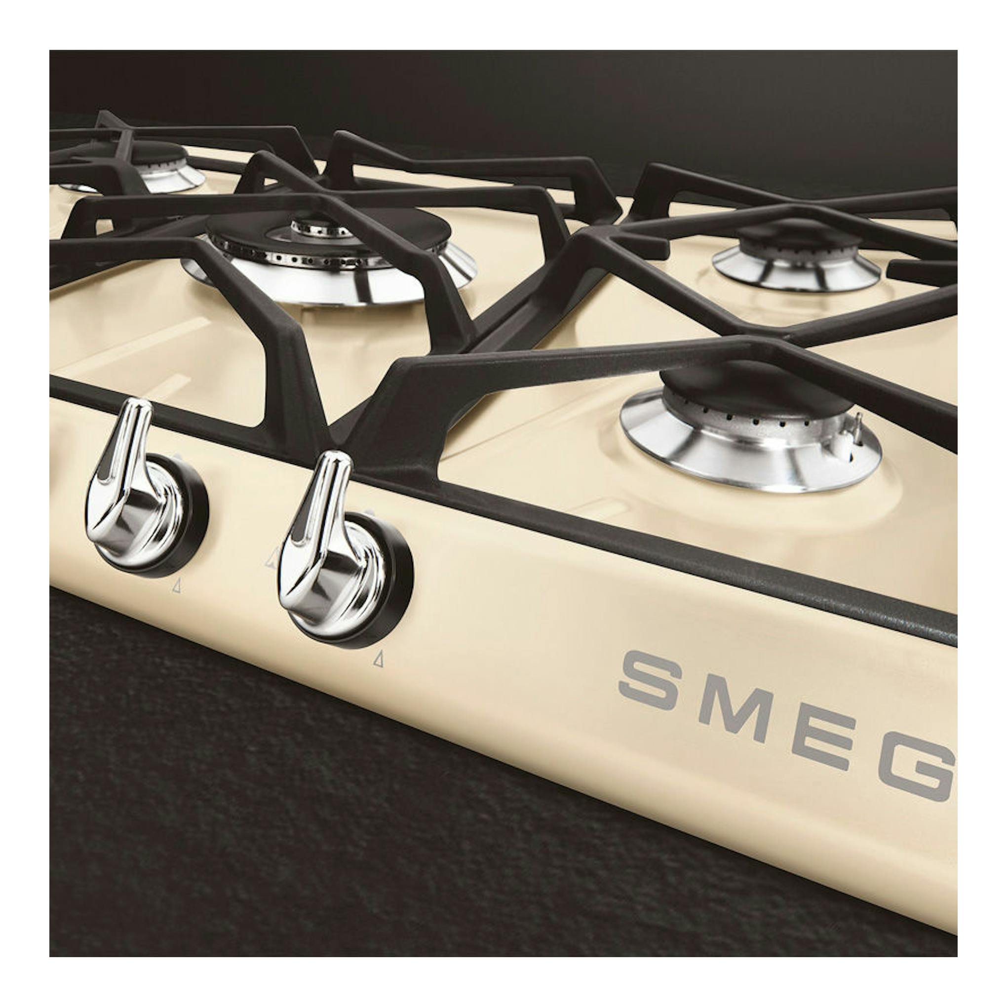 Placa de gas Smeg SR975PGH beige con cuatro fuegos y parrillas negras, vista en ángulo.