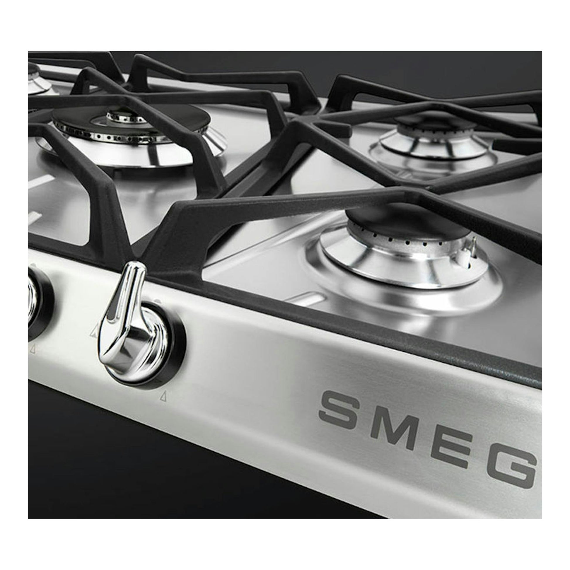 Placa de gas Smeg de acero inoxidable, vista en ángulo, con 4 quemadores y mandos frontales negros.