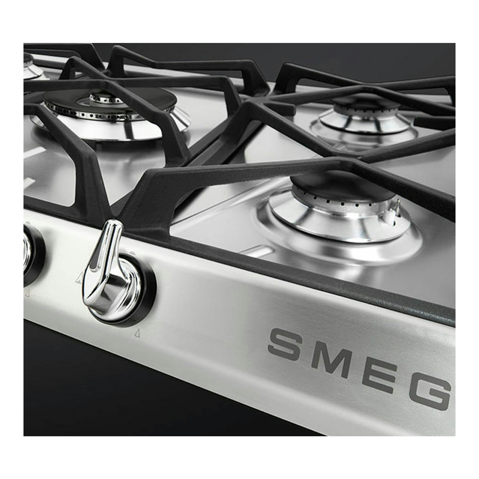 Placa de gas Smeg de acero inoxidable, vista en ángulo, con 4 quemadores y mandos frontales negros.