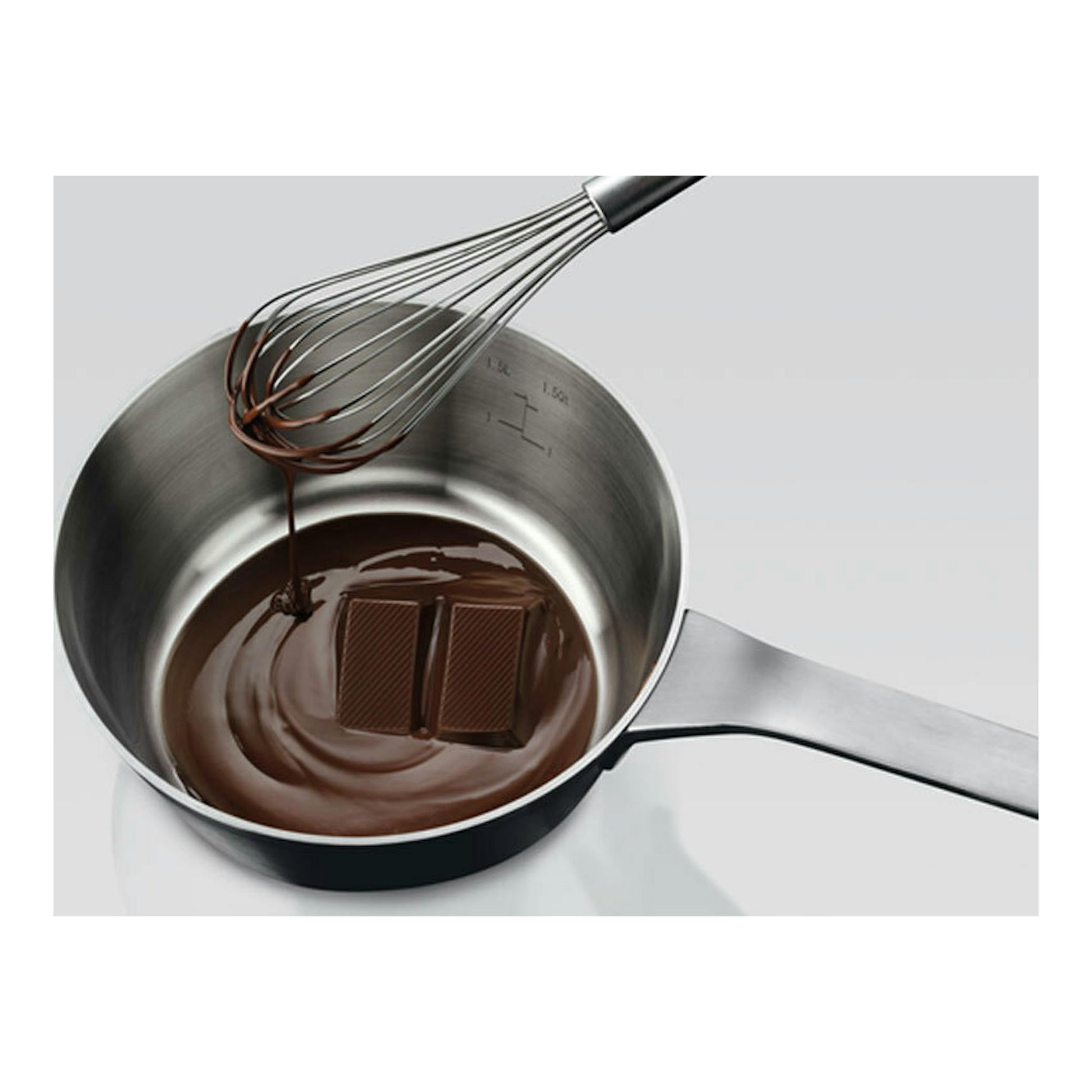 Vista cenital de un cazo de acero con chocolate derretido y varillas, para AEG IKB63300FW.