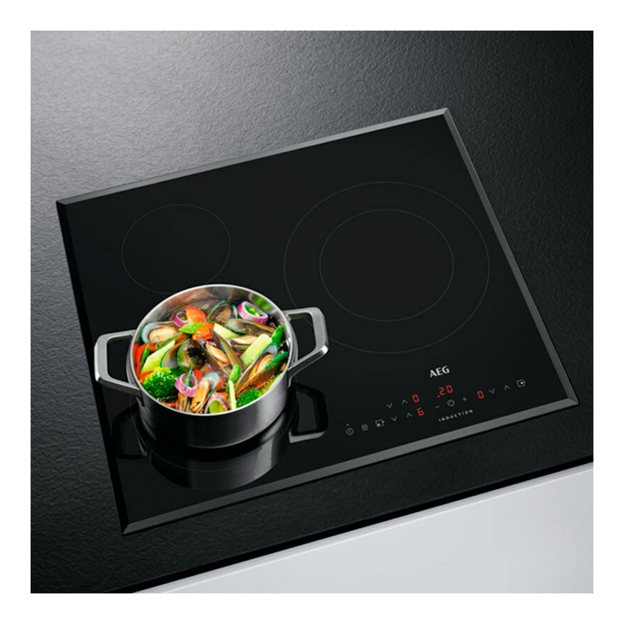 Placa de inducción AEG IKB63302FB negra, vista en ángulo, con una olla sobre una zona de cocción.