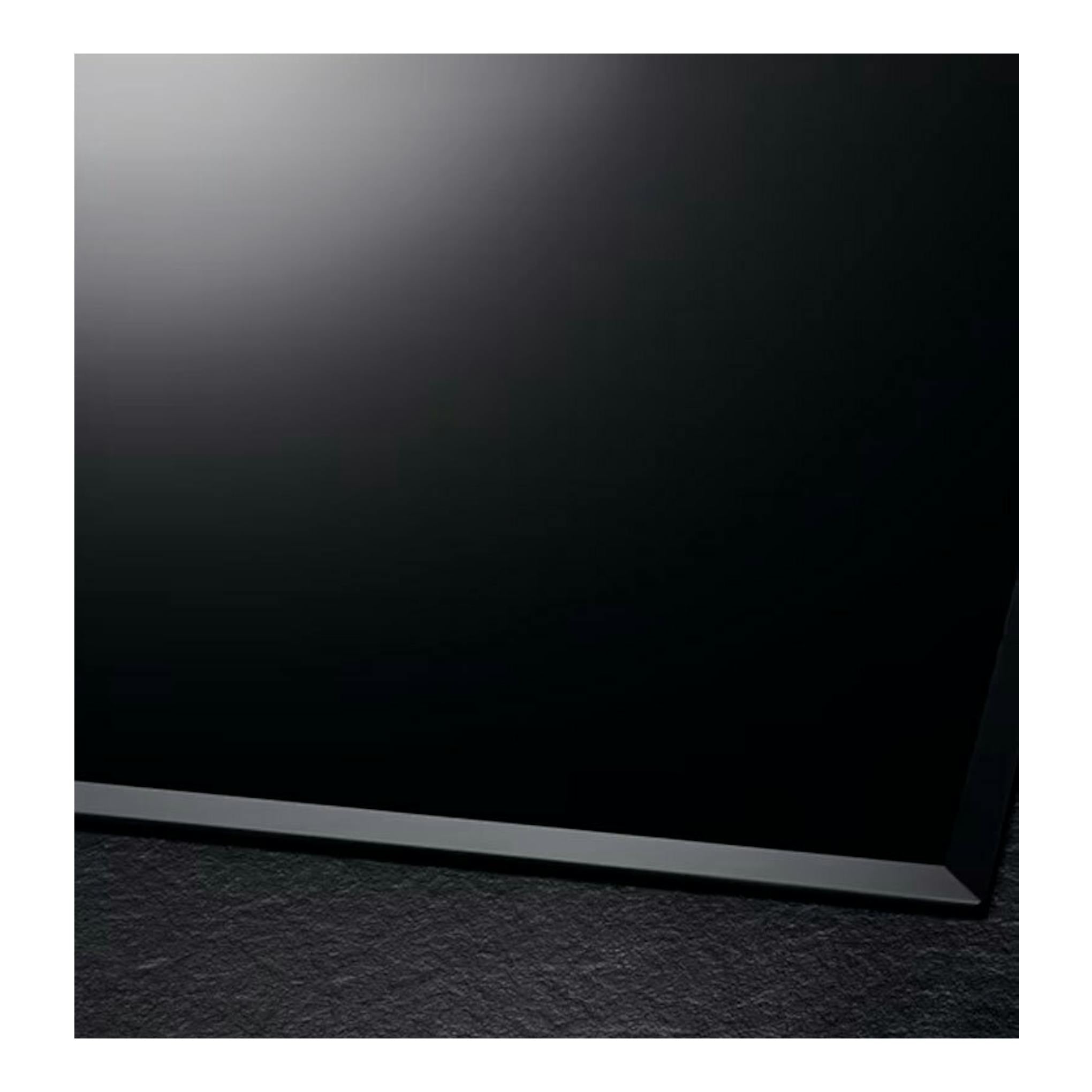 Placa de inducción AEG IKB63302FB negra, vista en ángulo de la esquina sobre fondo oscuro.