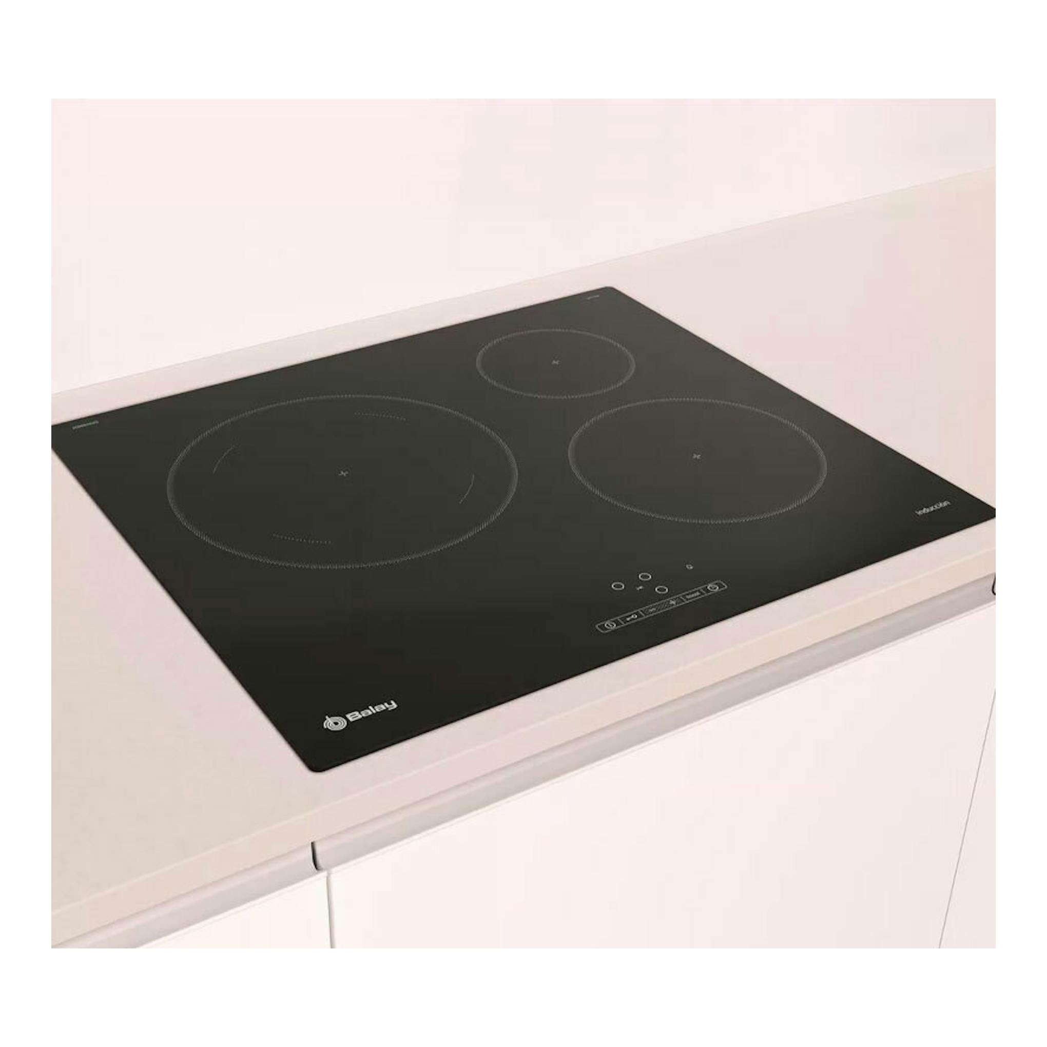 Placa de inducción Balay 3EB865ERS negra, vista en ángulo, con tres zonas de cocción.