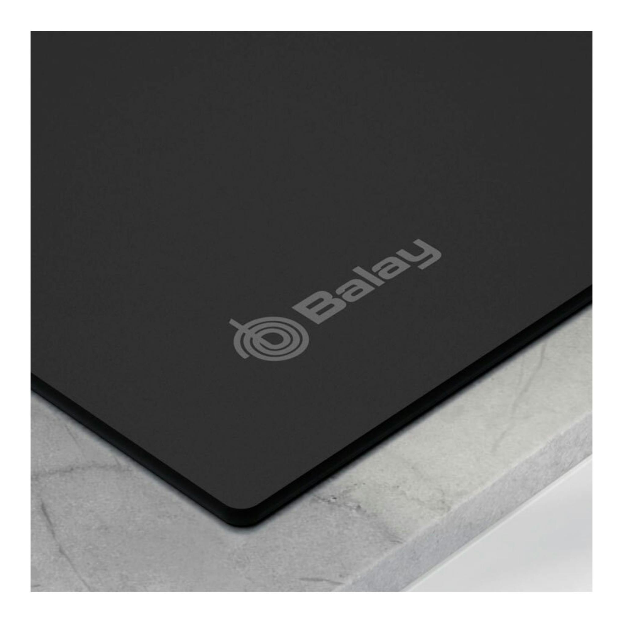 Placa de inducción Balay 3EB967MH negra, vista en ángulo de un borde sobre encimera gris.