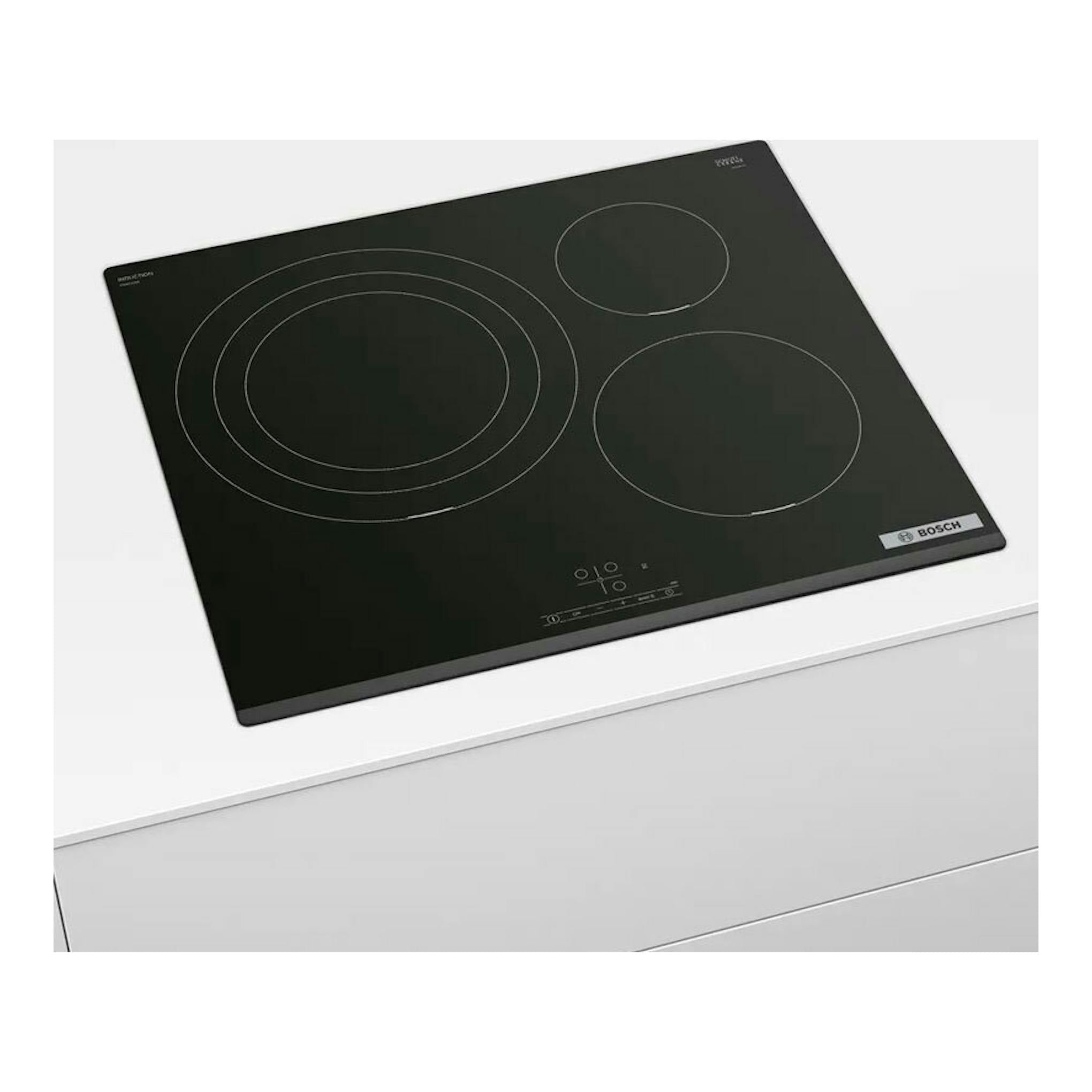 Placa de inducción Bosch PID631BB5E negra, vista en ángulo sobre encimera blanca.