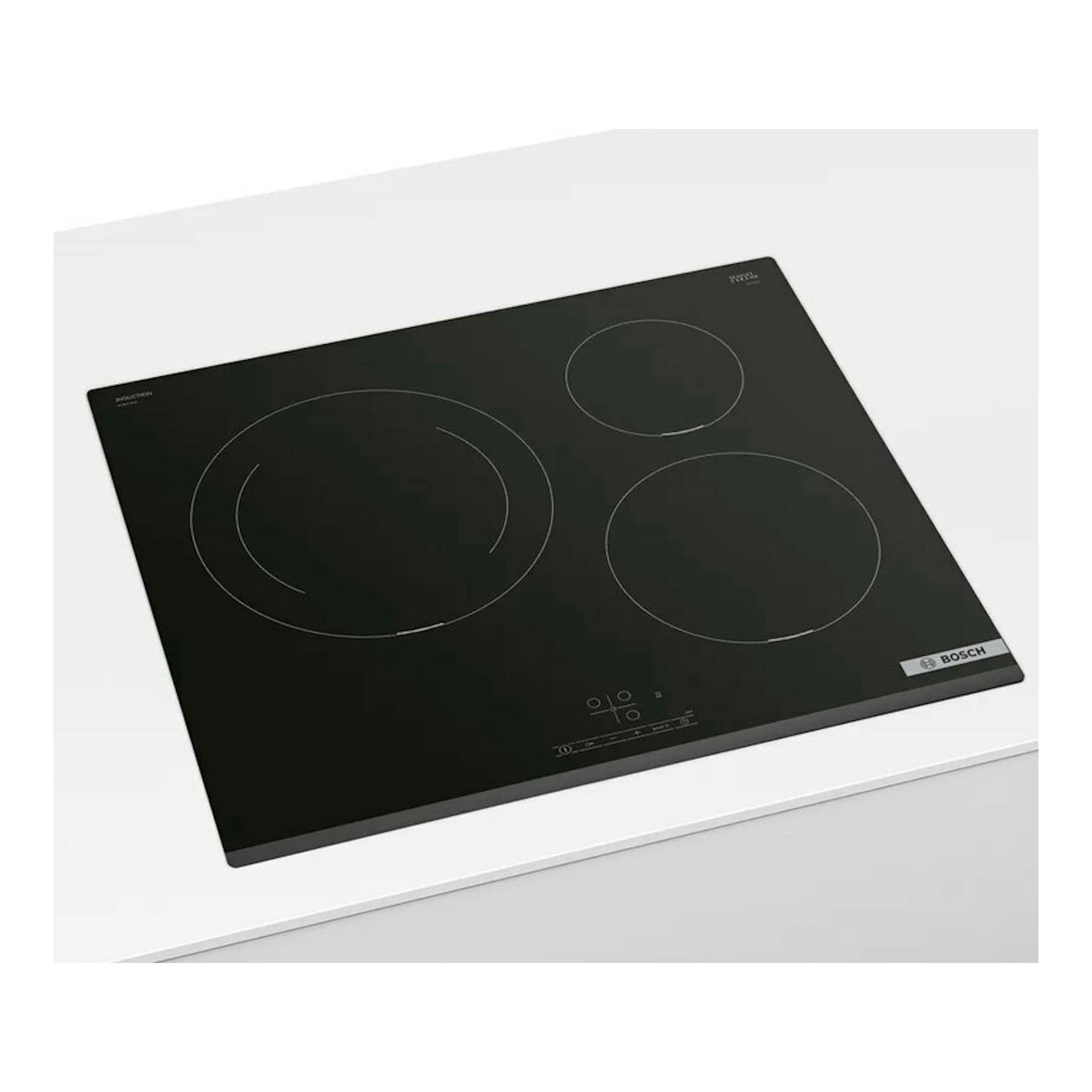 Placa de inducción Bosch PIJ631BB5E negra, vista en ángulo, con tres zonas de cocción.