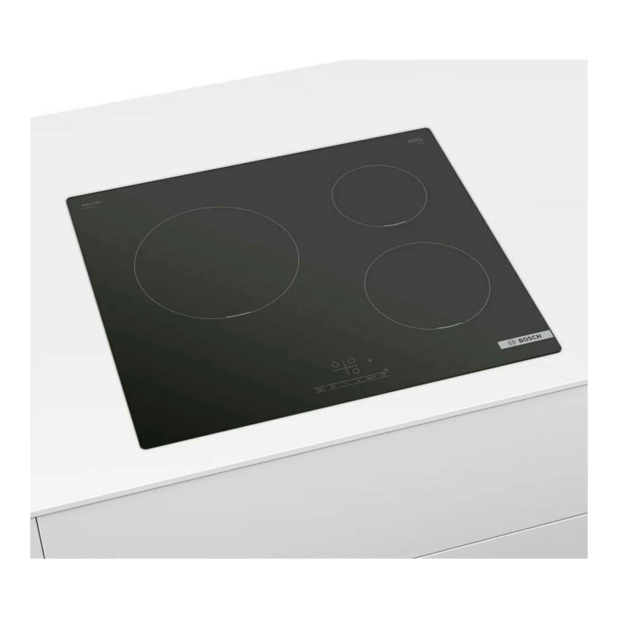 Placa de inducción Bosch PUC611BB5E negra, vista en ángulo superior, con tres zonas de cocción