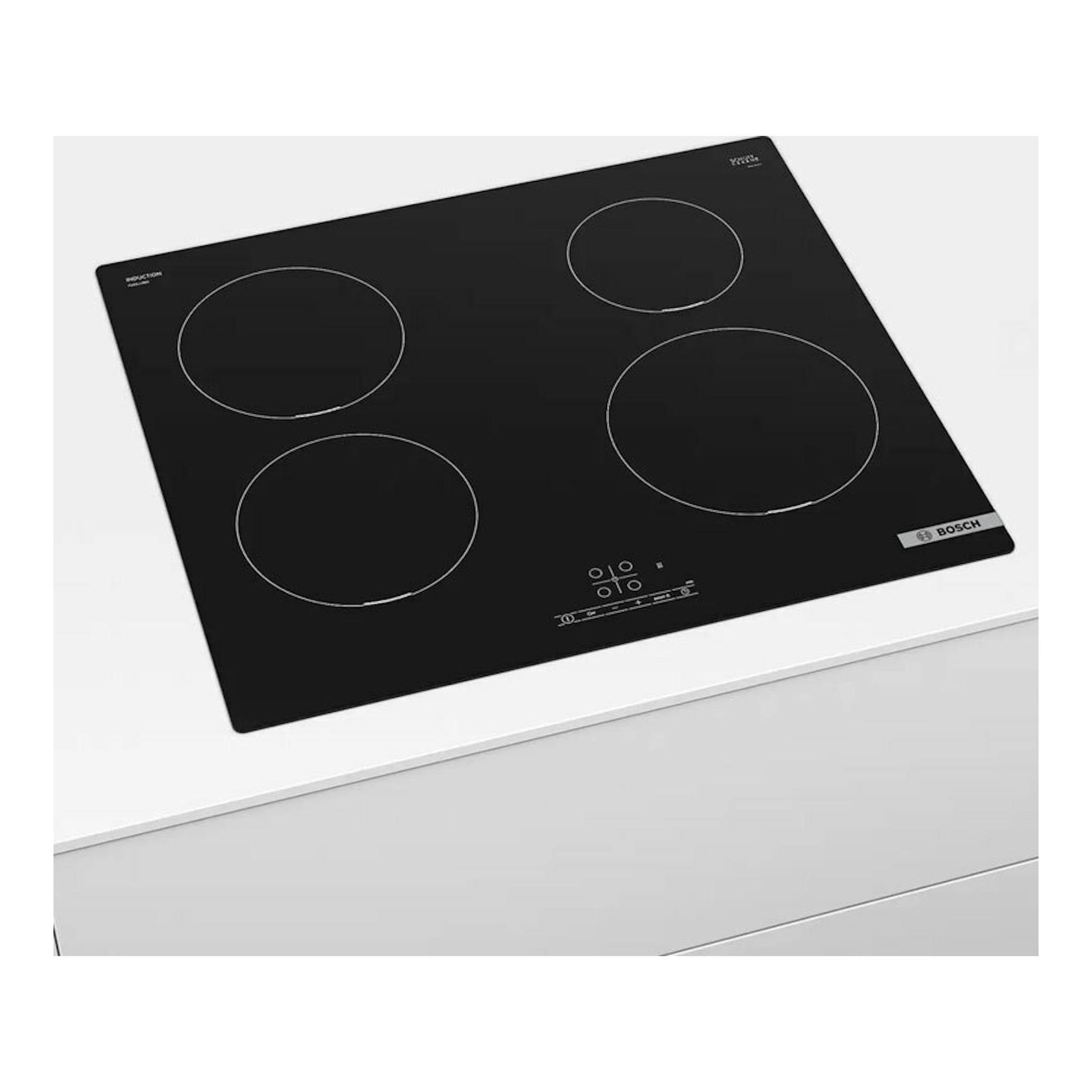 Placa de inducción Bosch PUE611BB5E negra, vista en ángulo sobre encimera blanca, con cuatro zonas.