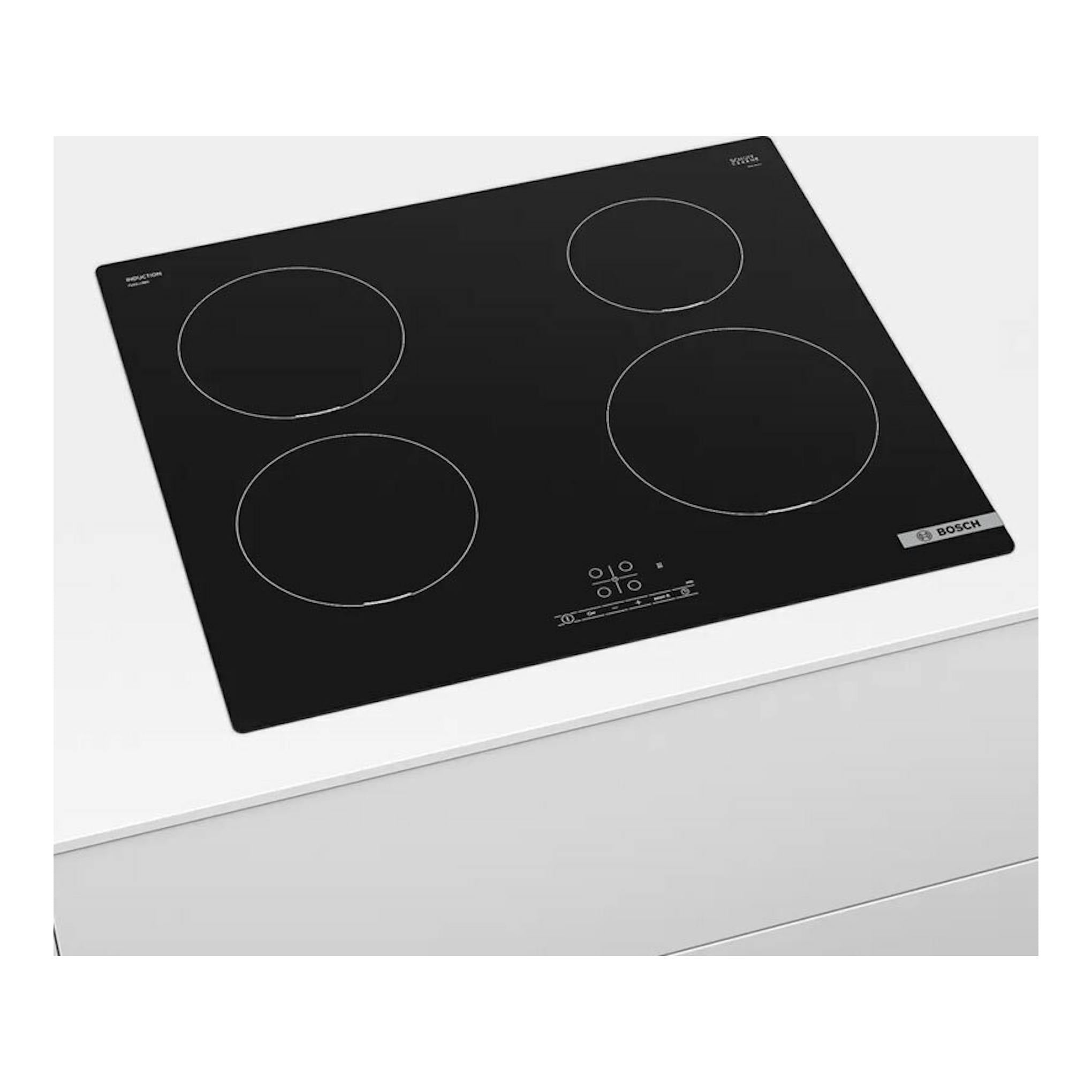 Placa de inducción Bosch PUE611BB5E negra, vista en ángulo sobre encimera blanca, con cuatro zonas.