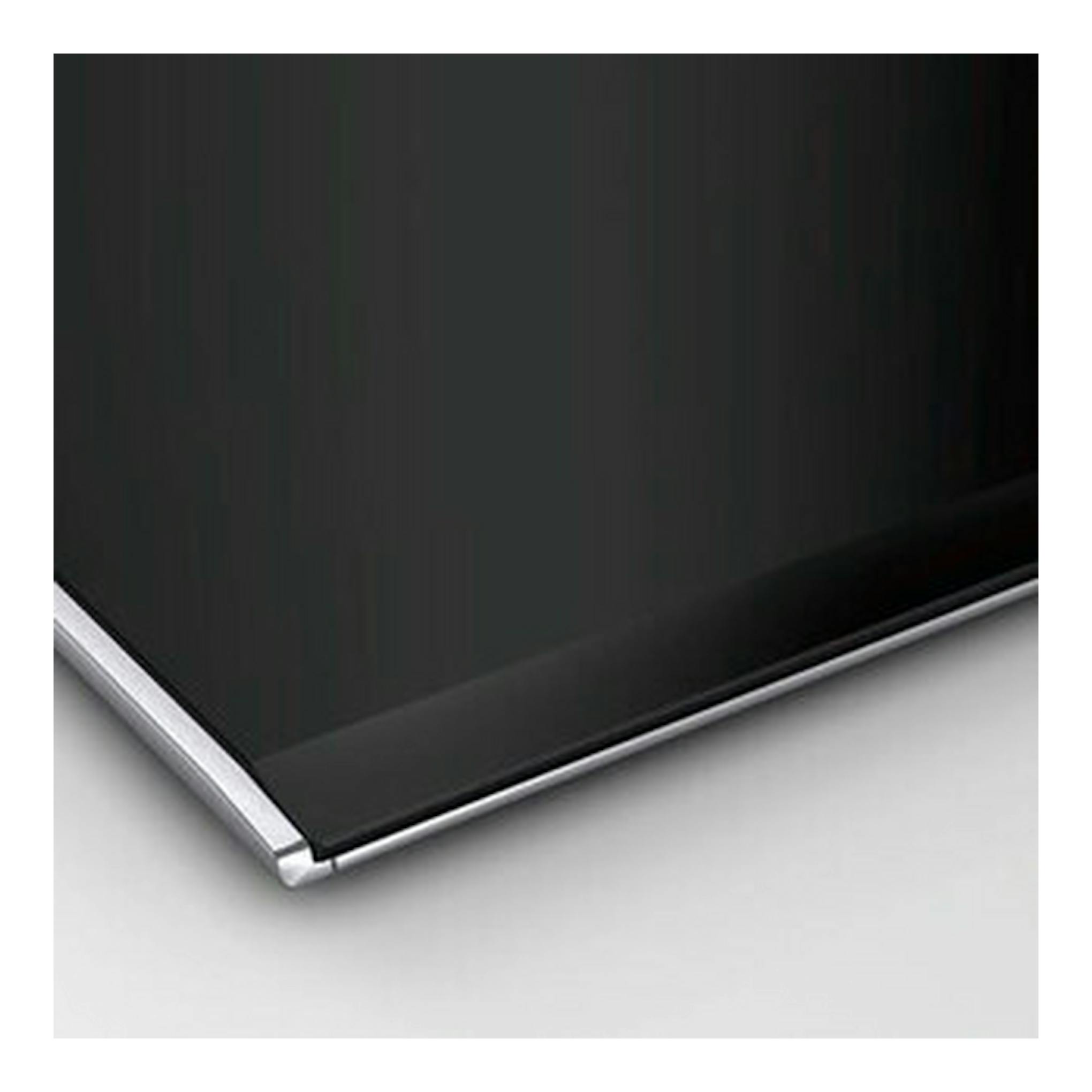 Placa de inducción Bosch PXY675DC1E negra, primer plano de una esquina con borde plateado.