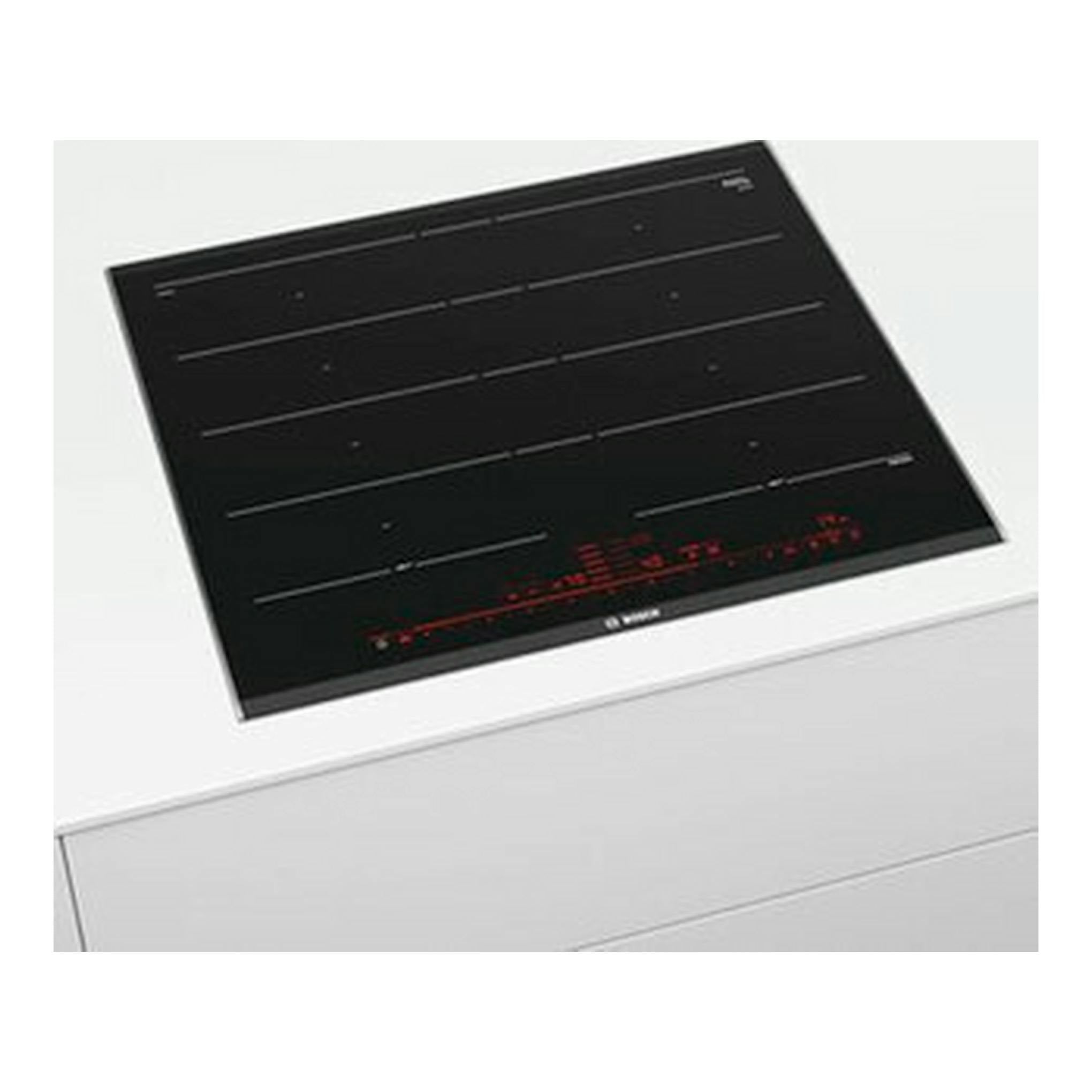 Placa de inducción Bosch PXY675DC1E negra, vista superior inclinada sobre encimera blanca.