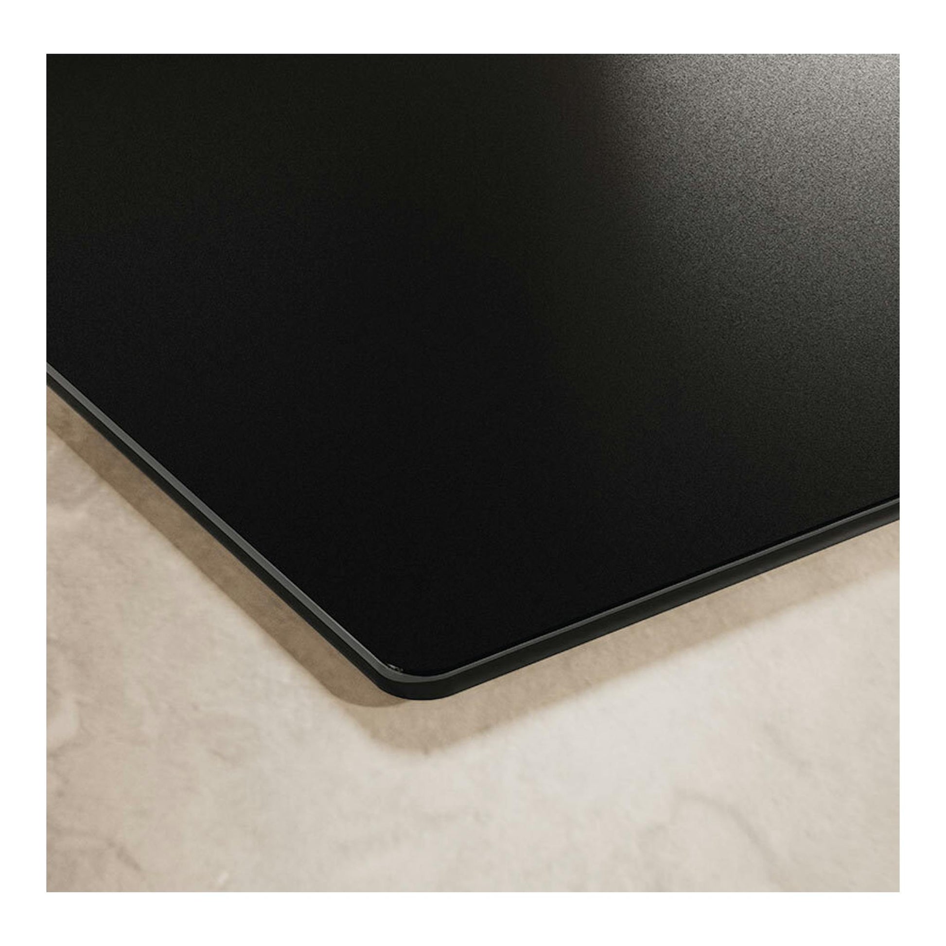 Placa de inducción Electrolux EIT61336CT negra, primer plano de una esquina con borde biselado.