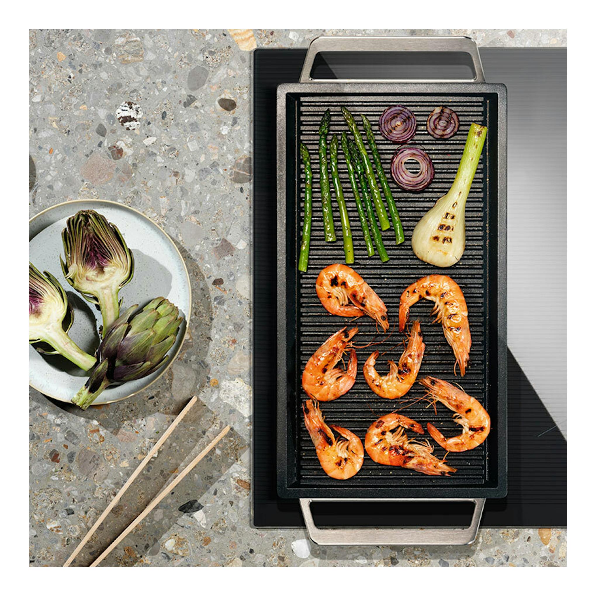 Placa de inducción Electrolux LIS62341, vista cenital, con plancha grill negra y alimentos.