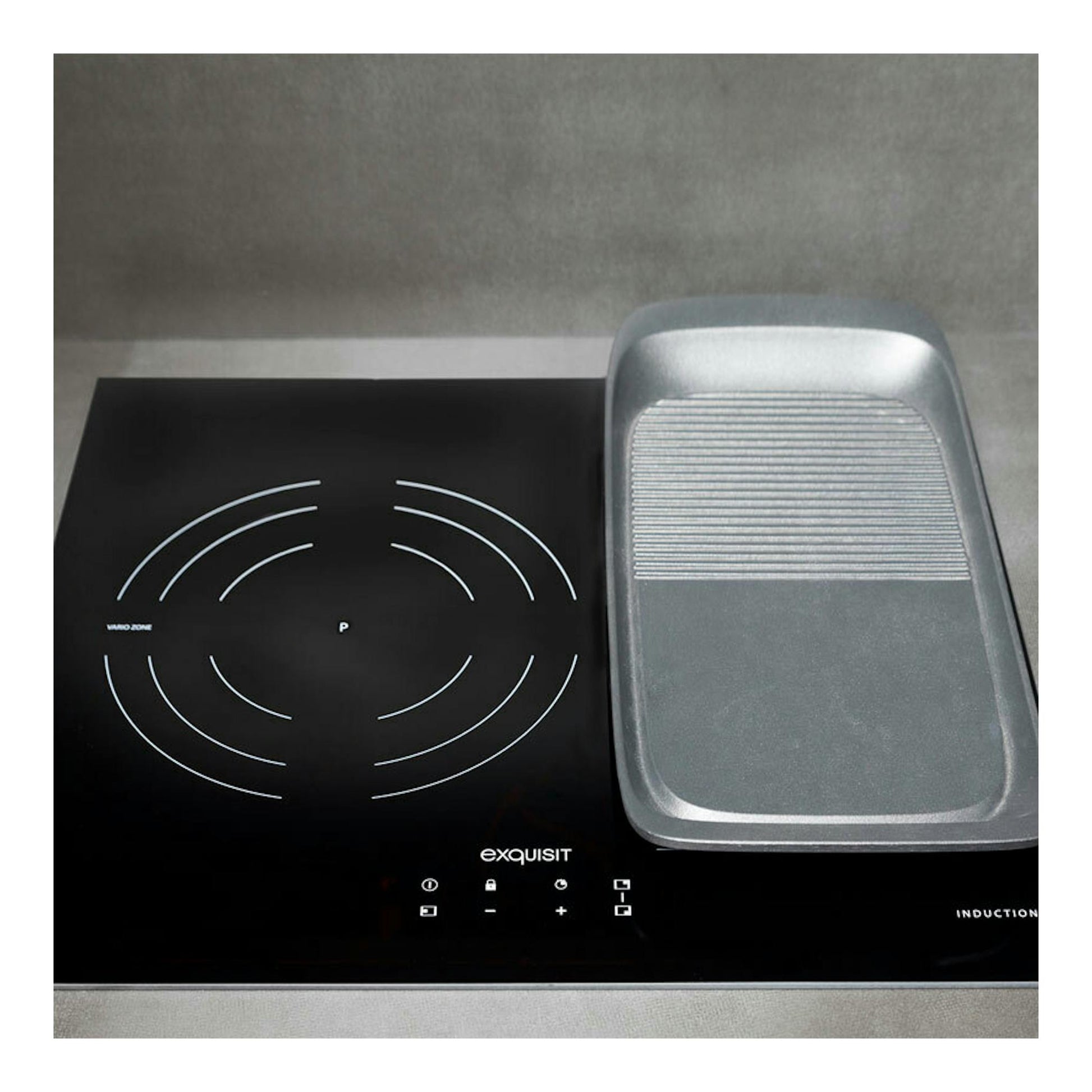 Placa de inducción Exquisit EKI 653F negra, vista frontal, con una bandeja/grill gris a la derecha.