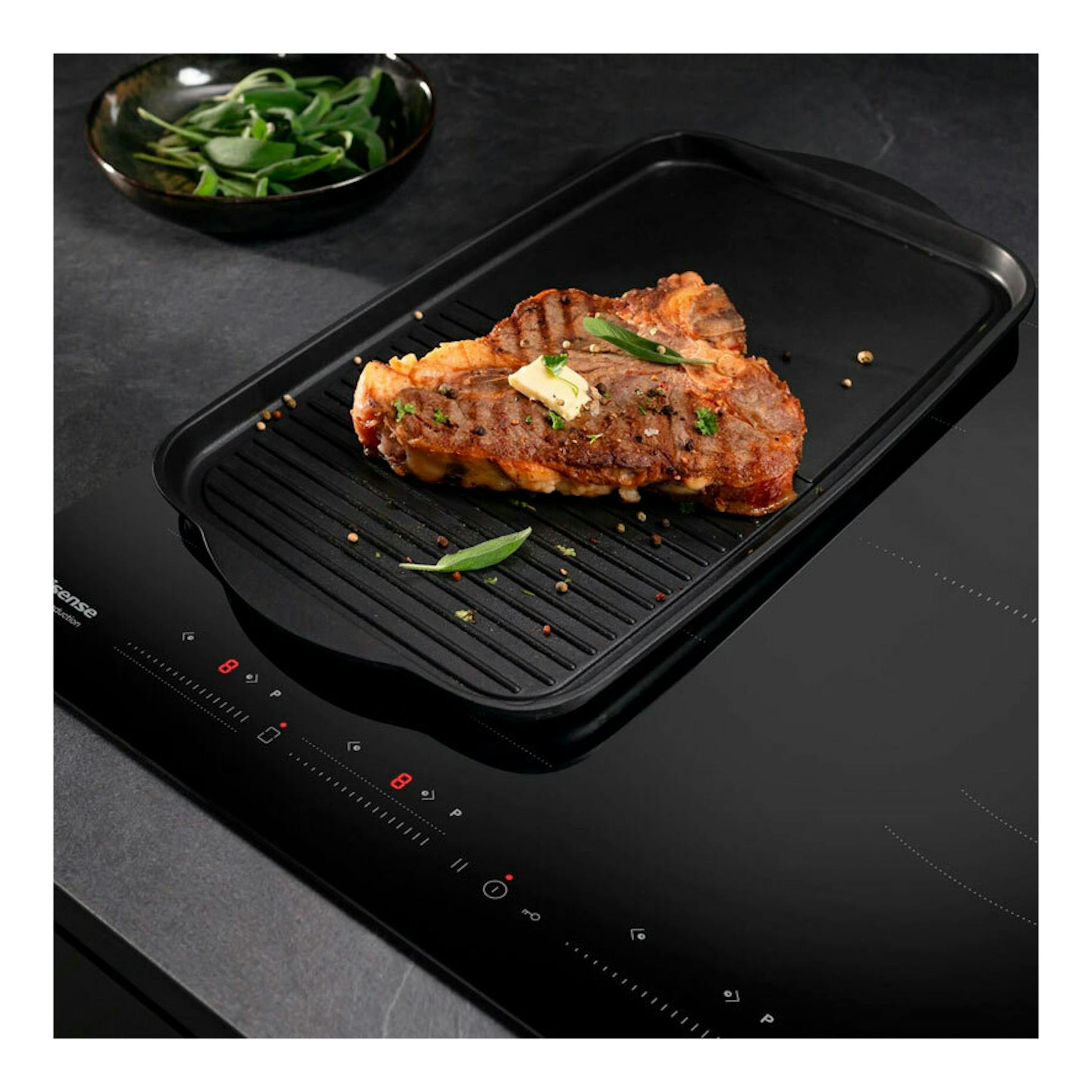 Placa de inducción Hisense HI6352BSCE negra, vista inclinada, con plancha y filete a la parrilla.