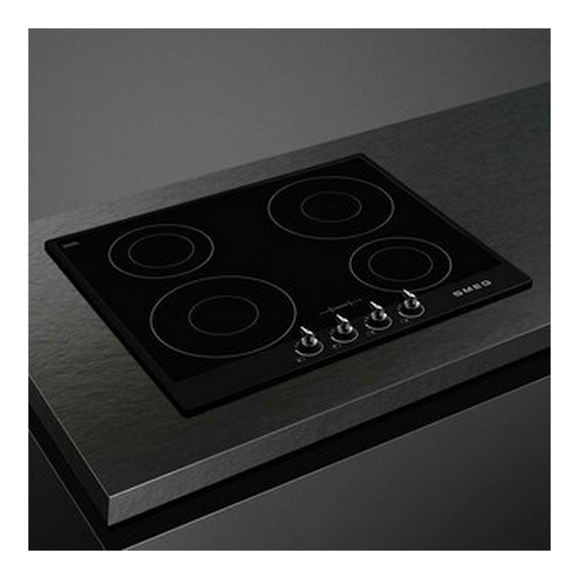 Placa de inducción Smeg SI964NM negra, vista en ángulo sobre encimera, con 4 zonas y mandos frontales.