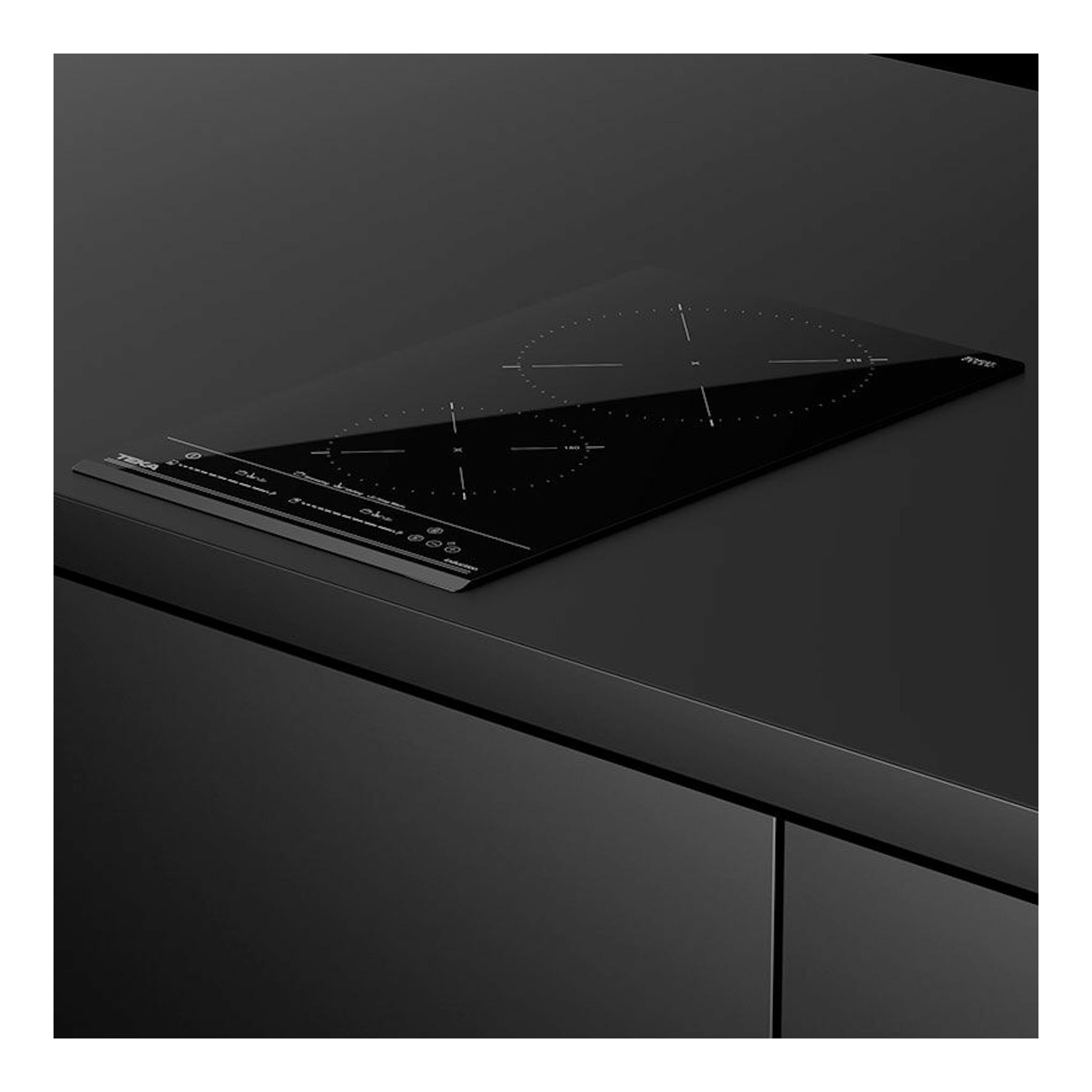 Placa de inducción Teka IZC 32310 MSP BK negra, vista en ángulo sobre encimera oscura.