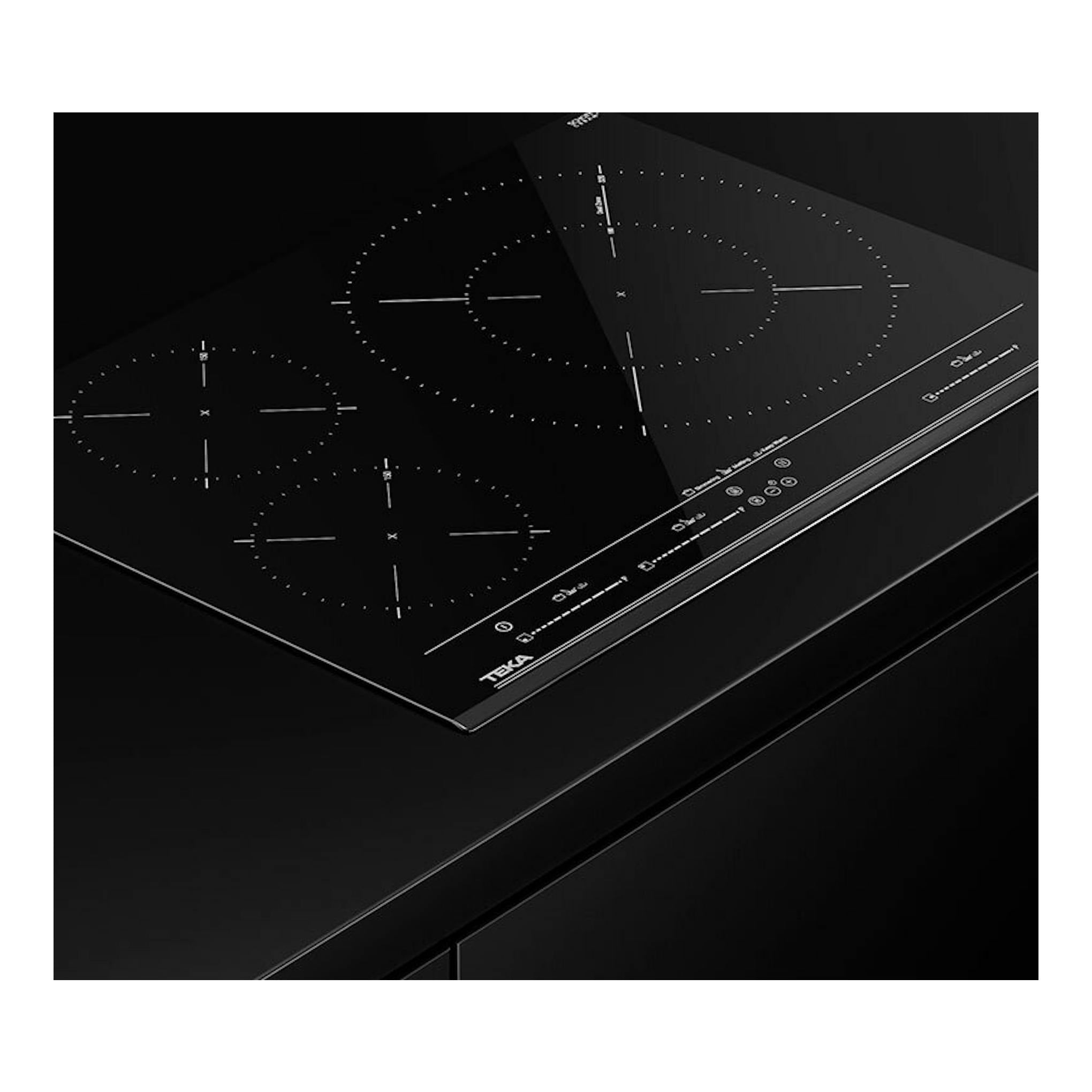 Placa de inducción Teka negra, vista superior en ángulo, con cuatro zonas de cocción y mandos táctiles.