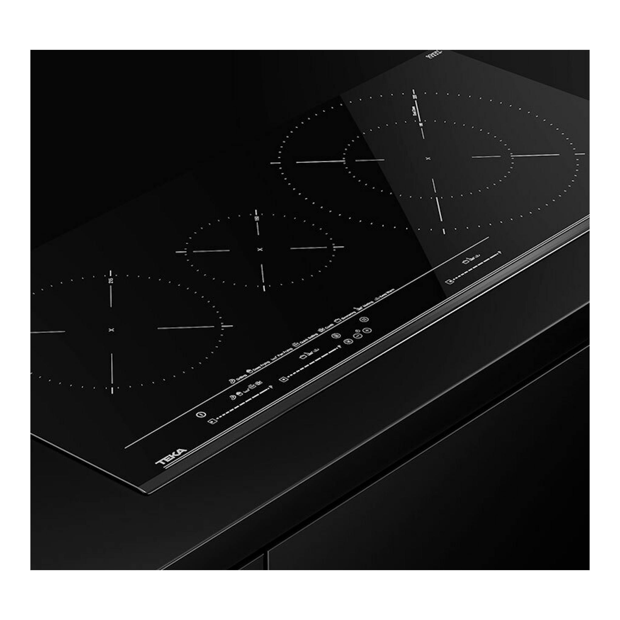 Placa de inducción Teka IZC93320MST negra, vista en ángulo, con cuatro zonas circulares de cocción.