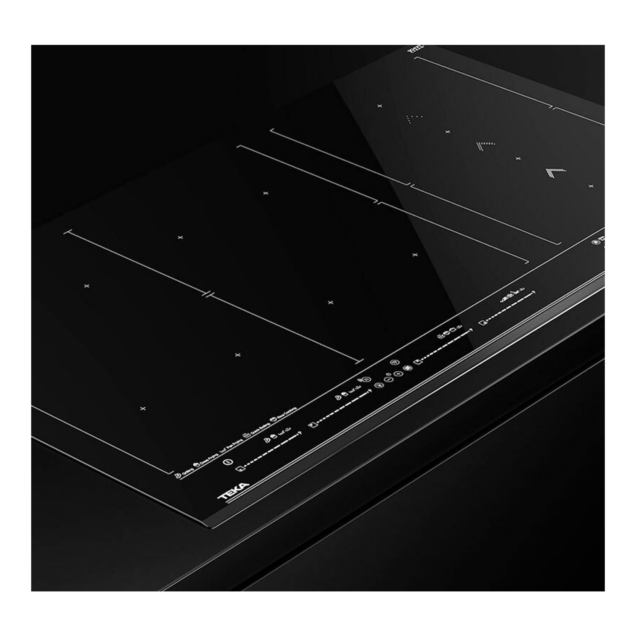 Placa de inducción Teka IZF99770MST BK negra, vista en ángulo sobre fondo oscuro.