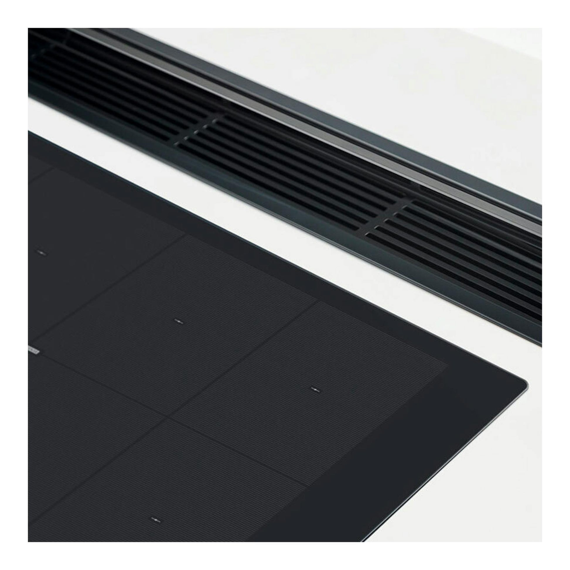 Placa de inducción Whirlpool SMO 658C/NE negra, vista en ángulo con superficie de vidrio y rejillas superiores.