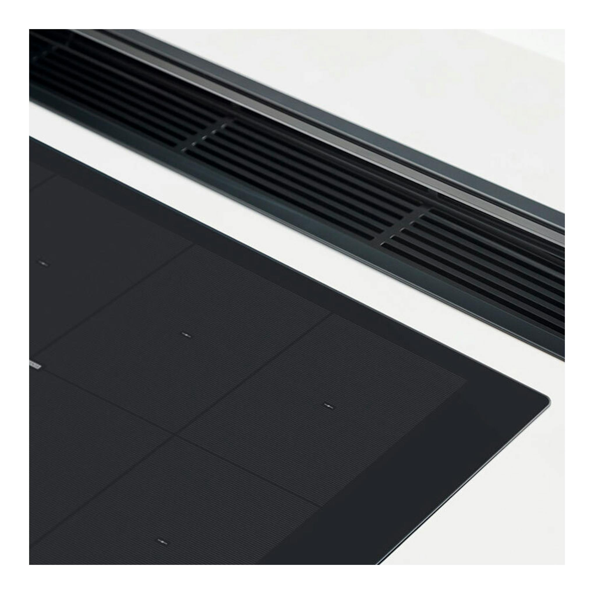 Placa de inducción Whirlpool SMO 658C/NE negra, vista en ángulo con superficie de vidrio y rejillas superiores.
