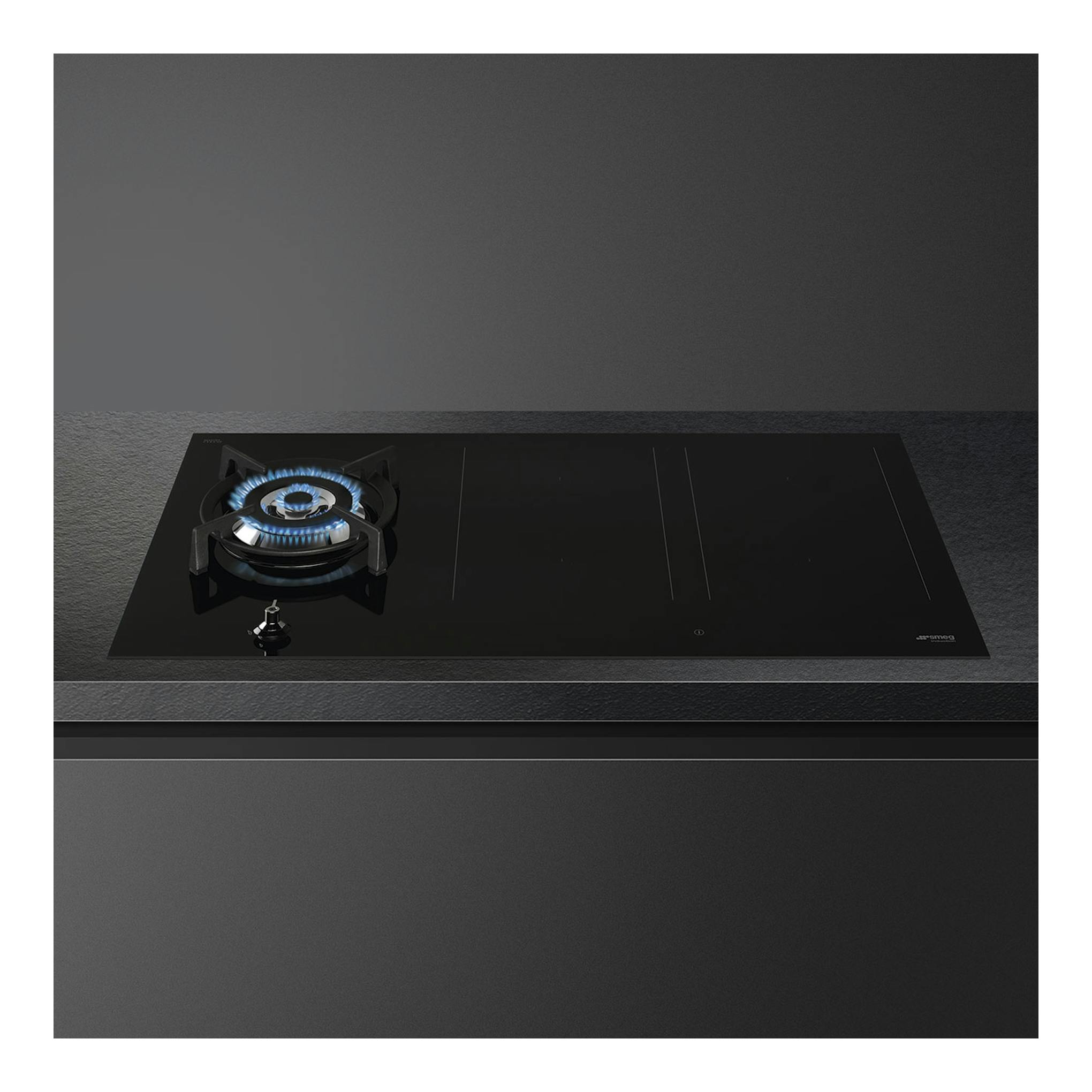 Placa de cocción Smeg PM3953D negra, vista en ángulo, con un quemador de gas y zonas de inducción.