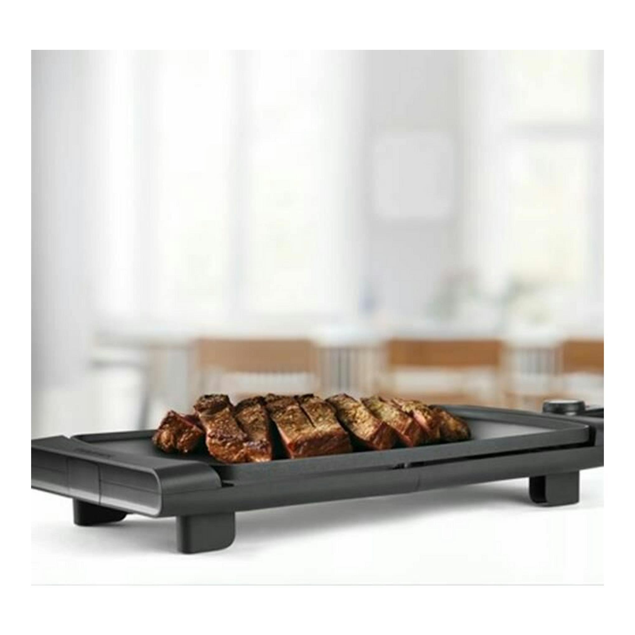 Plancha de asar Taurus Steakmax 2600 negra, en vista en ángulo, con carne asada.