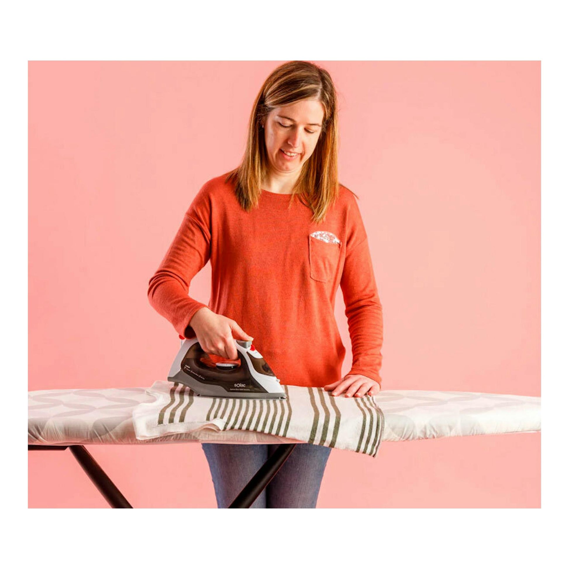 Mujer planchando una prenda con una plancha de vapor Solac PV2400 sobre una tabla de planchar, vista frontal.