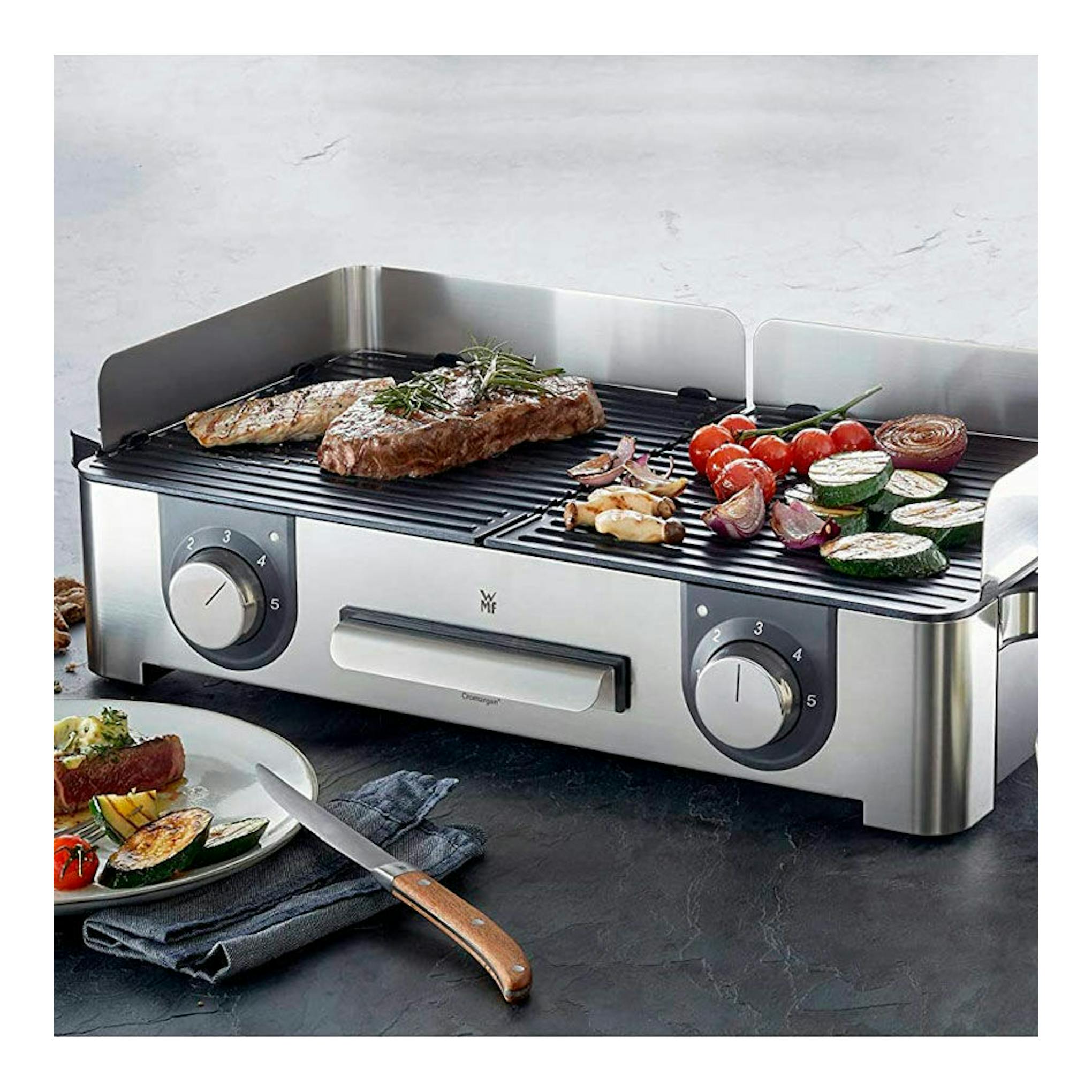 Plancha grill eléctrica WMF Master Grill LONO, vista frontal, acero inoxidable con alimentos en la parrilla.