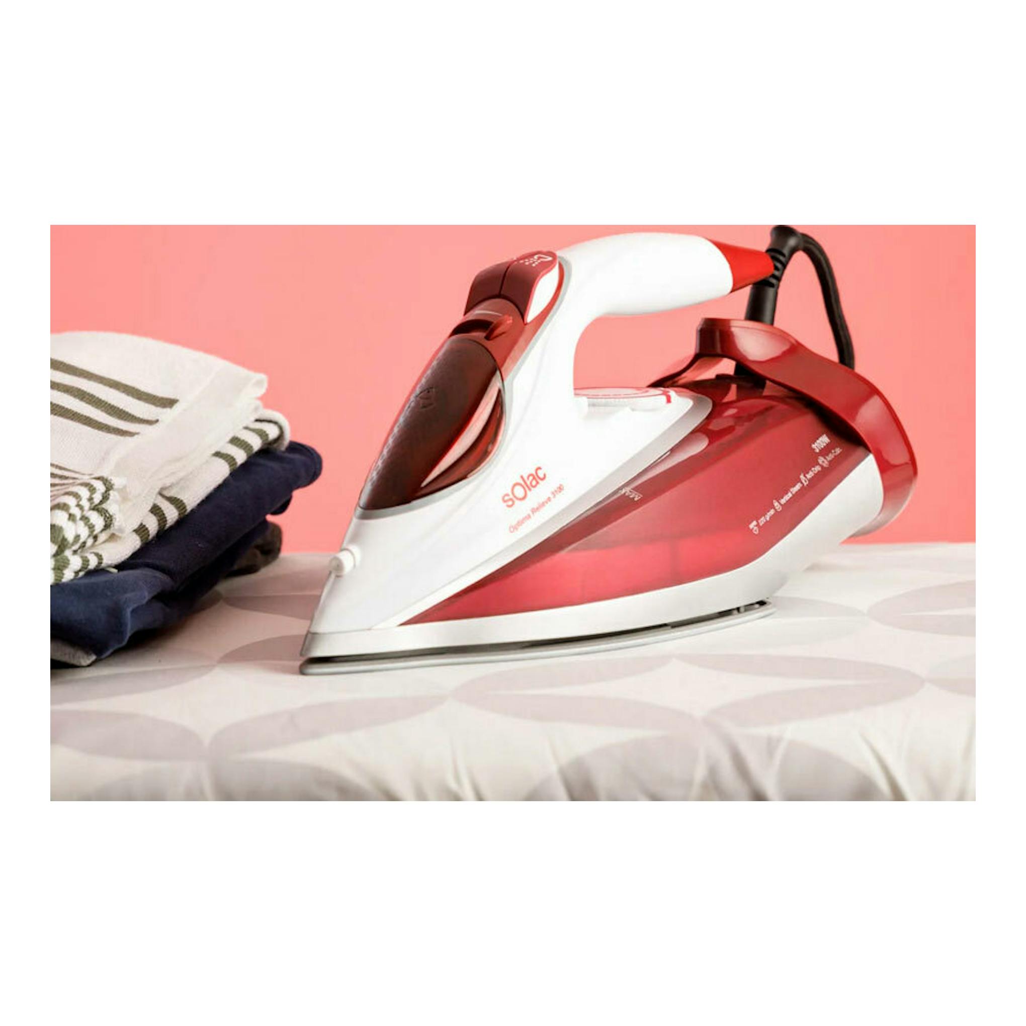 Plancha de vapor Solac PV2040 Relieve 3100, vista lateral, blanca y roja, sobre tabla con ropa doblada.