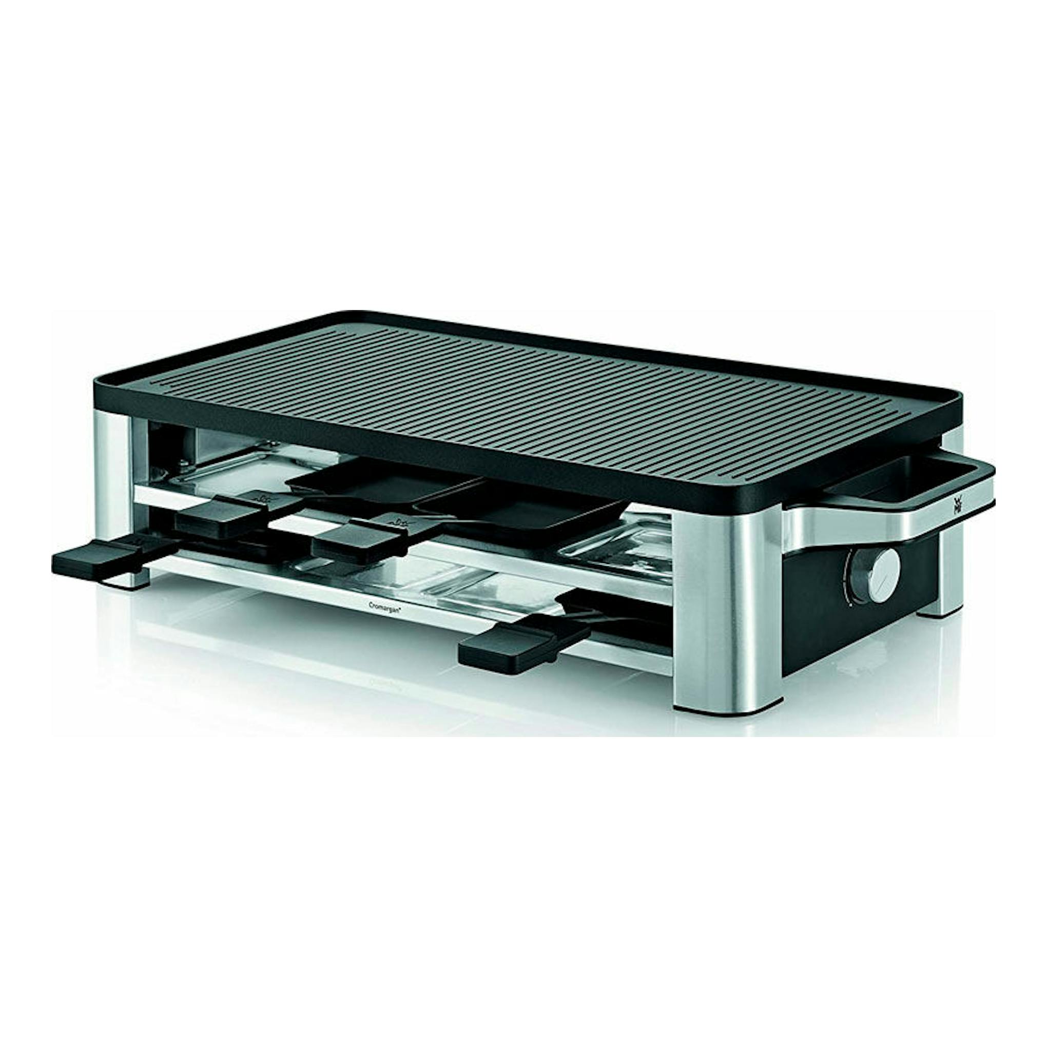 Raclette WMF Lono negra y plateada, vista en 3/4, con parrilla superior y bandejas inferiores.