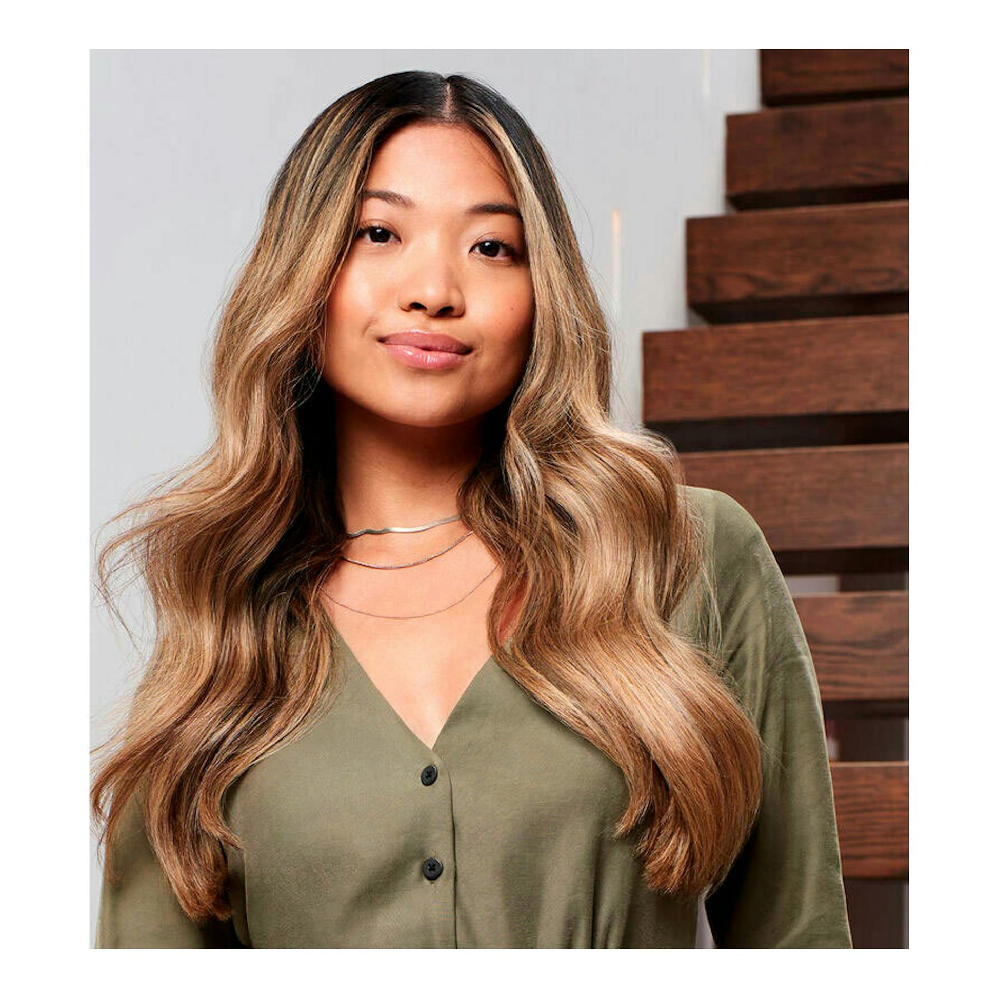 Mujer con cabello ondulado castaño claro, vista frontal, con blusa verde oliva.