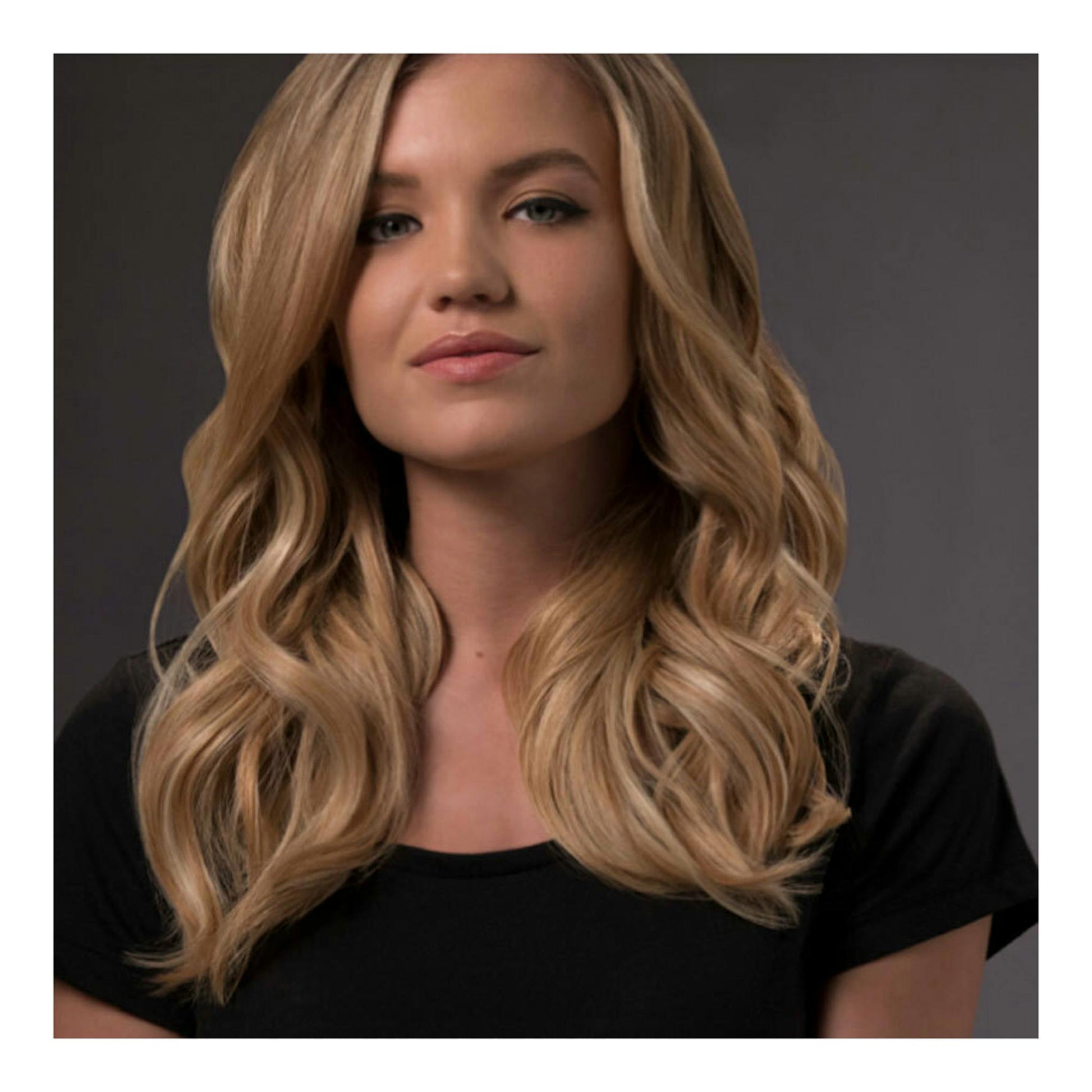 Mujer con cabello rubio ondulado, vista frontal, con camiseta negra.
