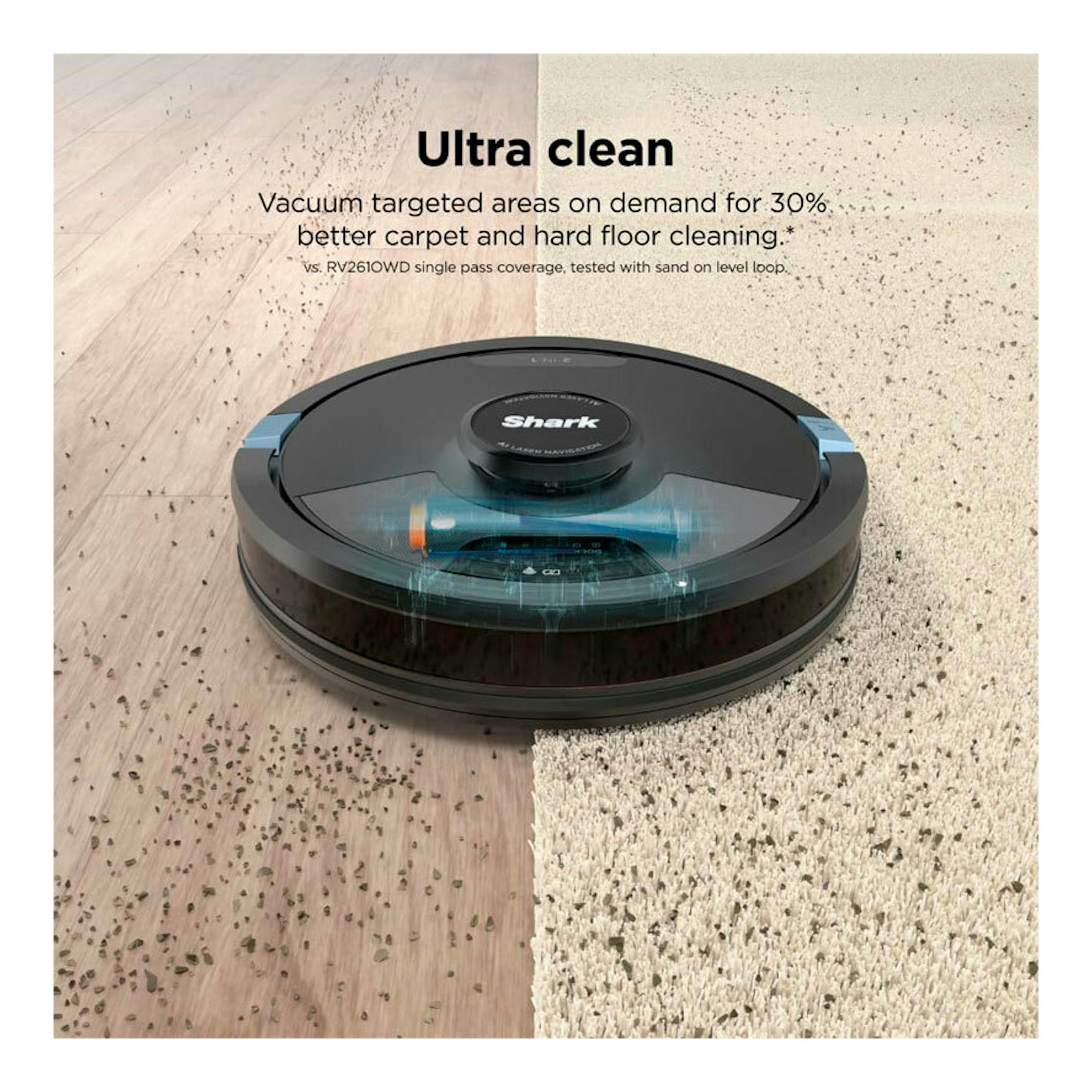 Robot aspirador Shark RV2620WAEU negro sobre suelo de madera y alfombra con arena, visto en ángulo frontal.