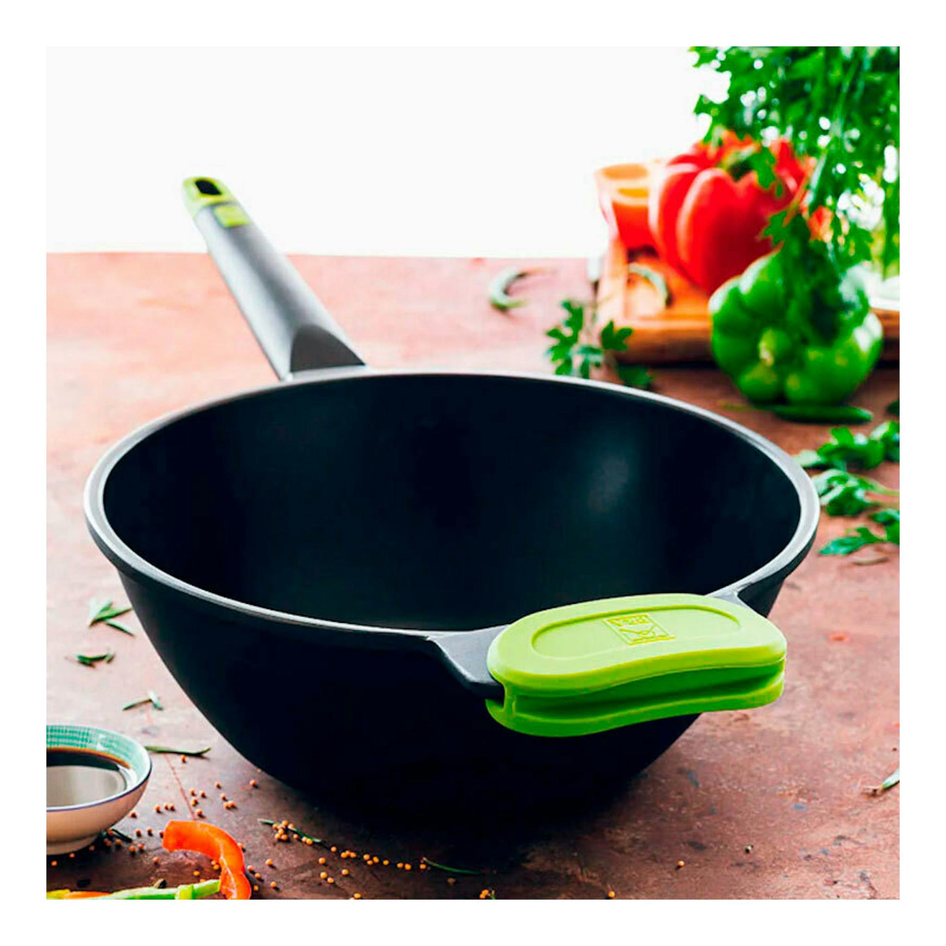 Wok Bra Foodie de 28 cm, negro, con mango verde, vista frontal sobre una mesa.