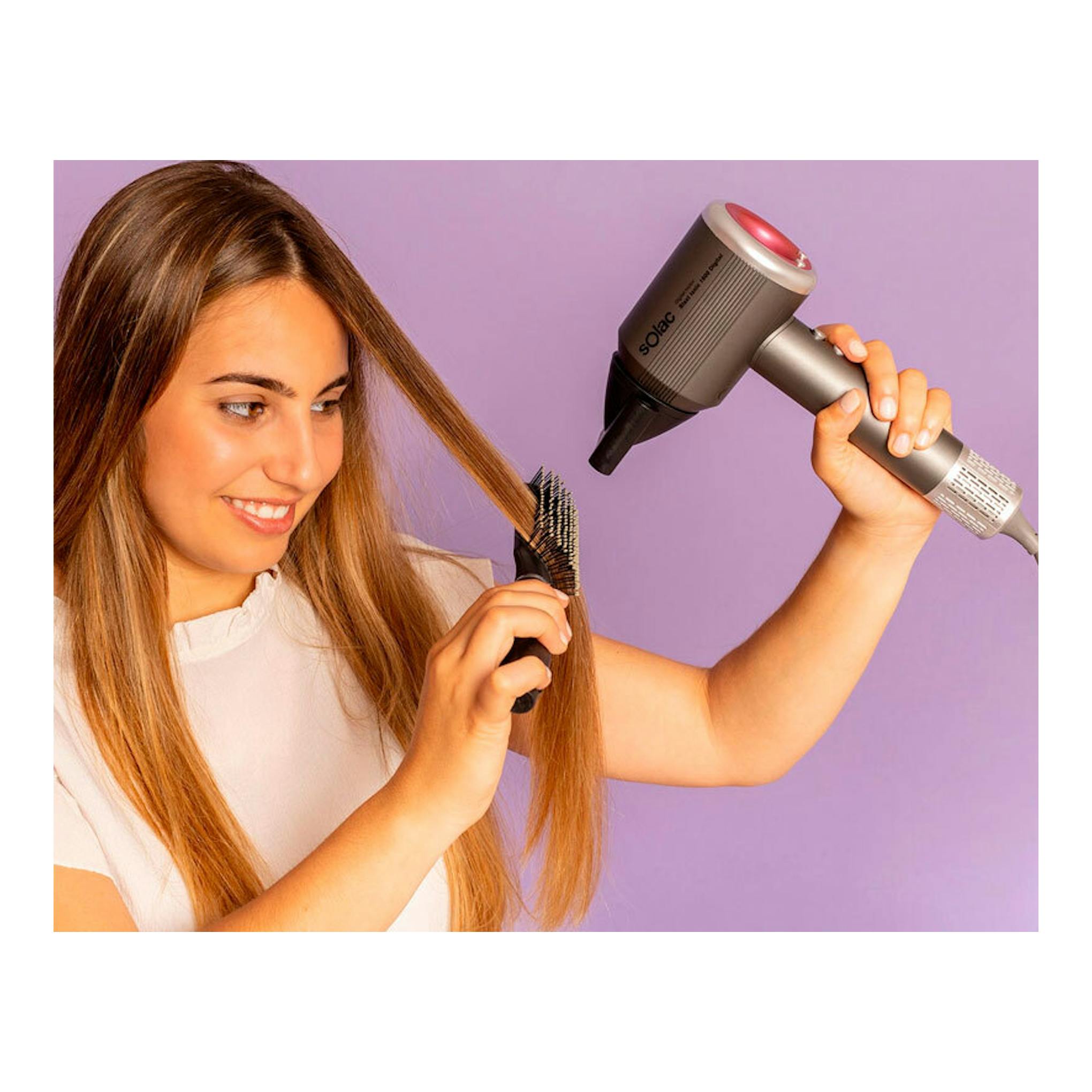 Secador Solac SB7950 Blast Ionic 1600 Digital en mano, junto a una mujer peinando su cabello, vista lateral.