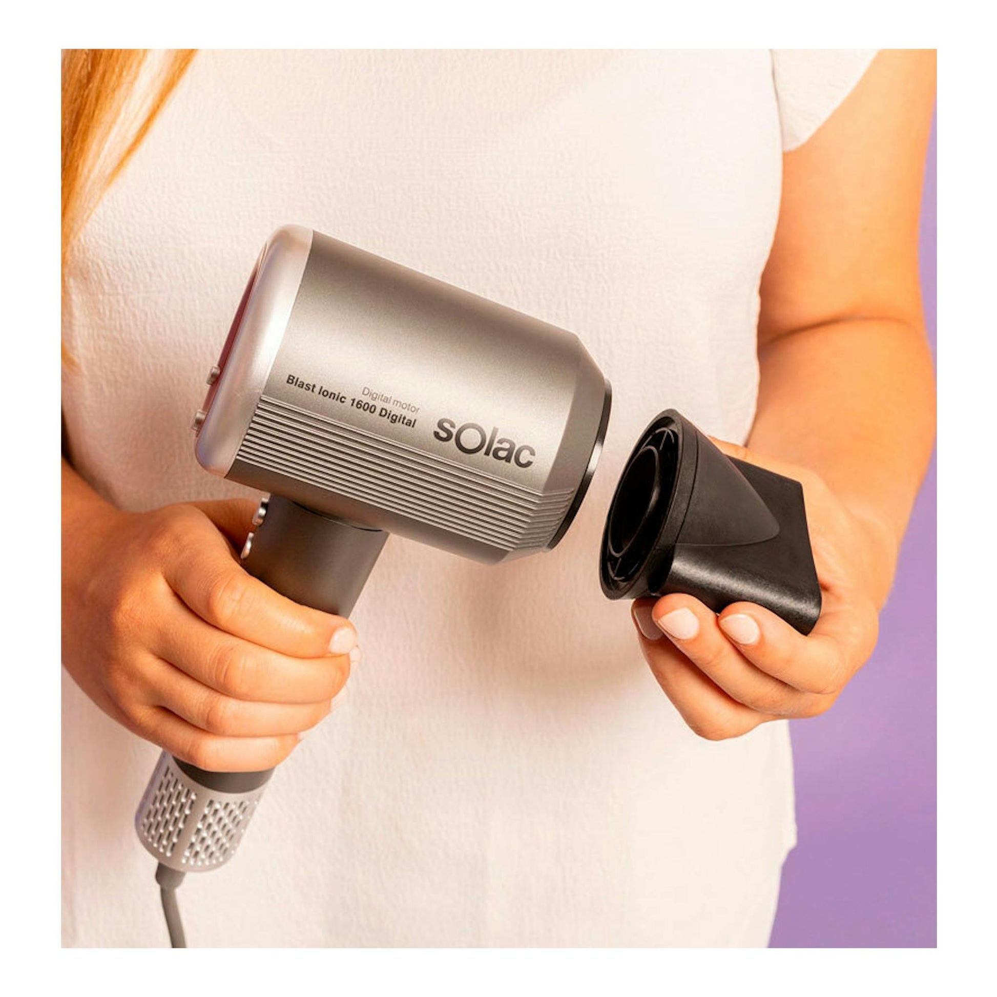 Secador Solac SB7950 Blast Ionic 1600 Digital gris, sujetado por una persona junto a un accesorio negro.