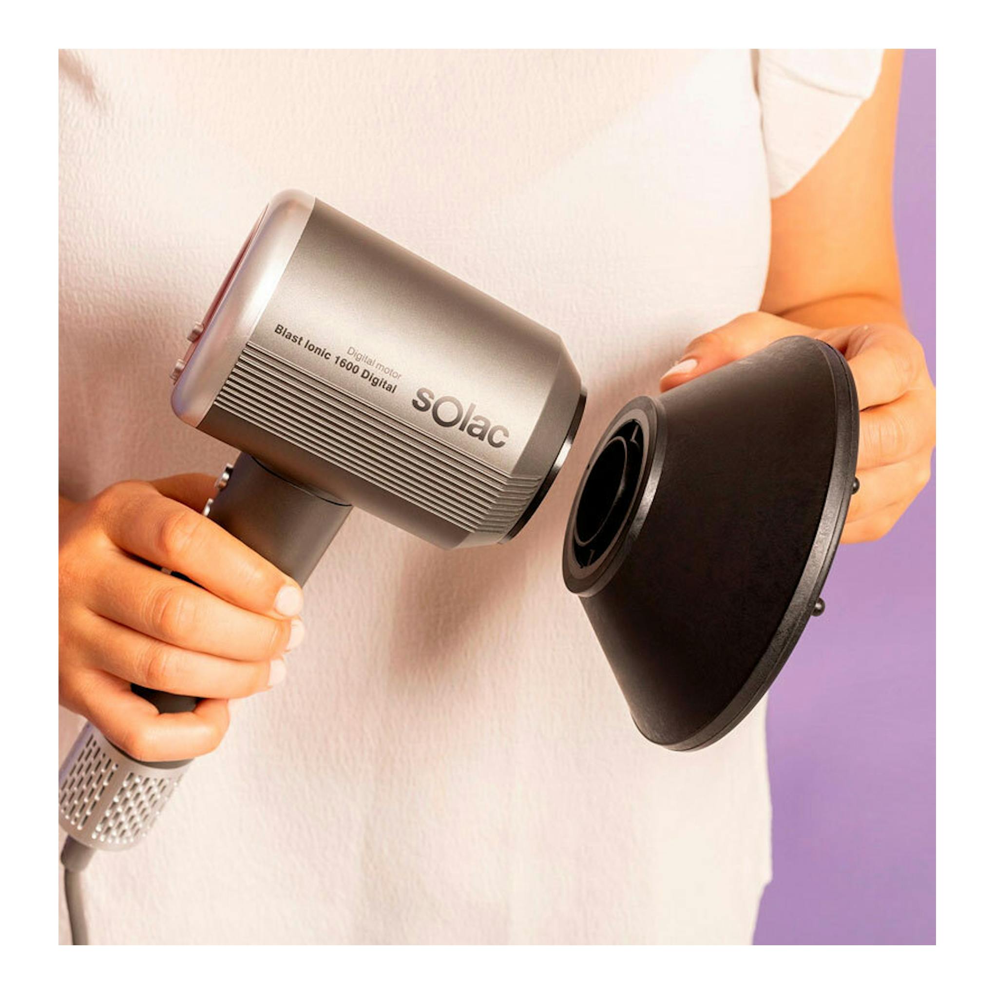 Secador Solac SB7950 Blast Ionic 1600 Digital gris, sostenido con una mano junto a un difusor negro.