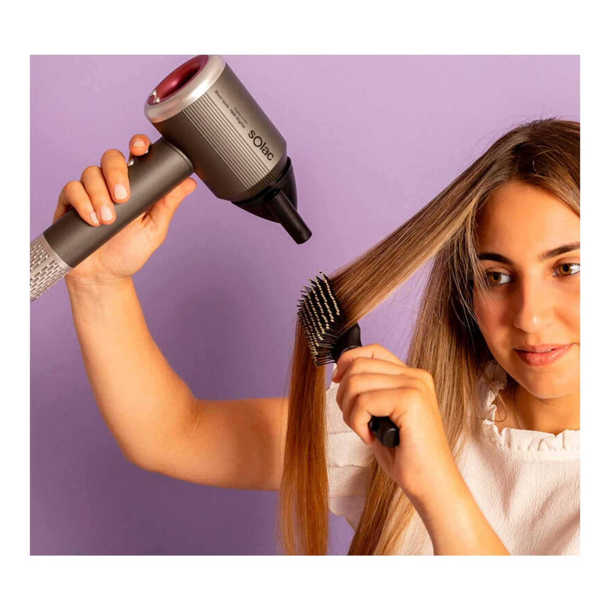 Secador Solac SB7950 Blast Ionic 1600 Digital gris, en uso con cepillo, junto a una mujer peinándose de perfil.