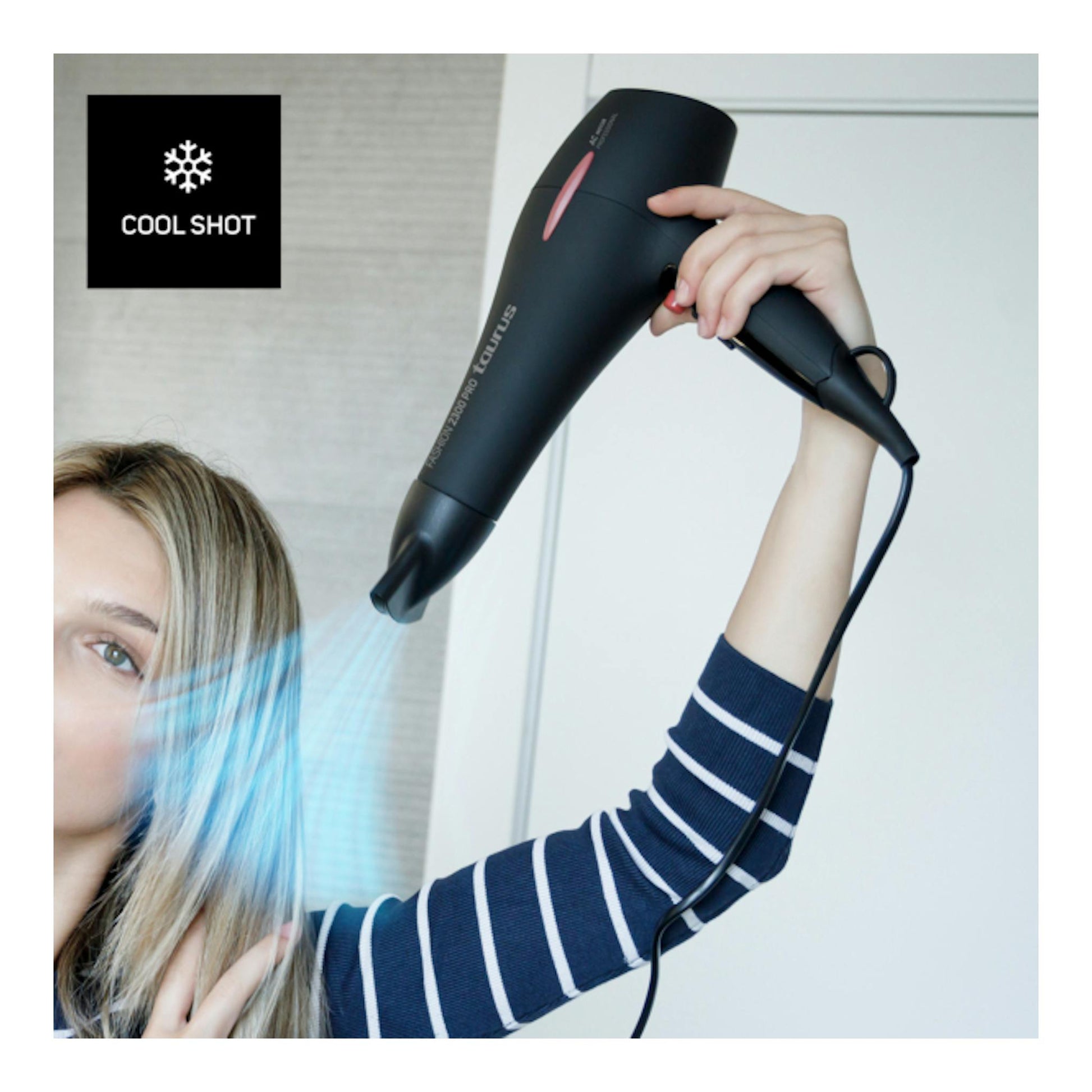 Secador de pelo Taurus Fashion 2300 Pro negro, en uso, con mano sujetándolo y aire frío.