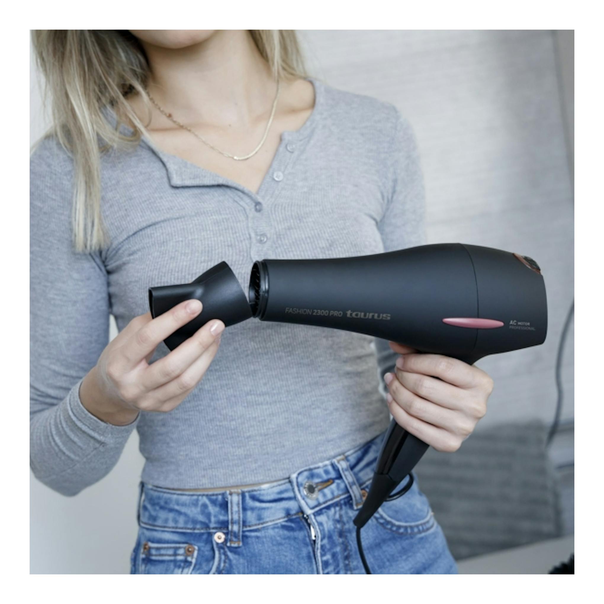 Secador de pelo negro Taurus Fashion 2300 Pro en manos de una mujer, vista lateral.