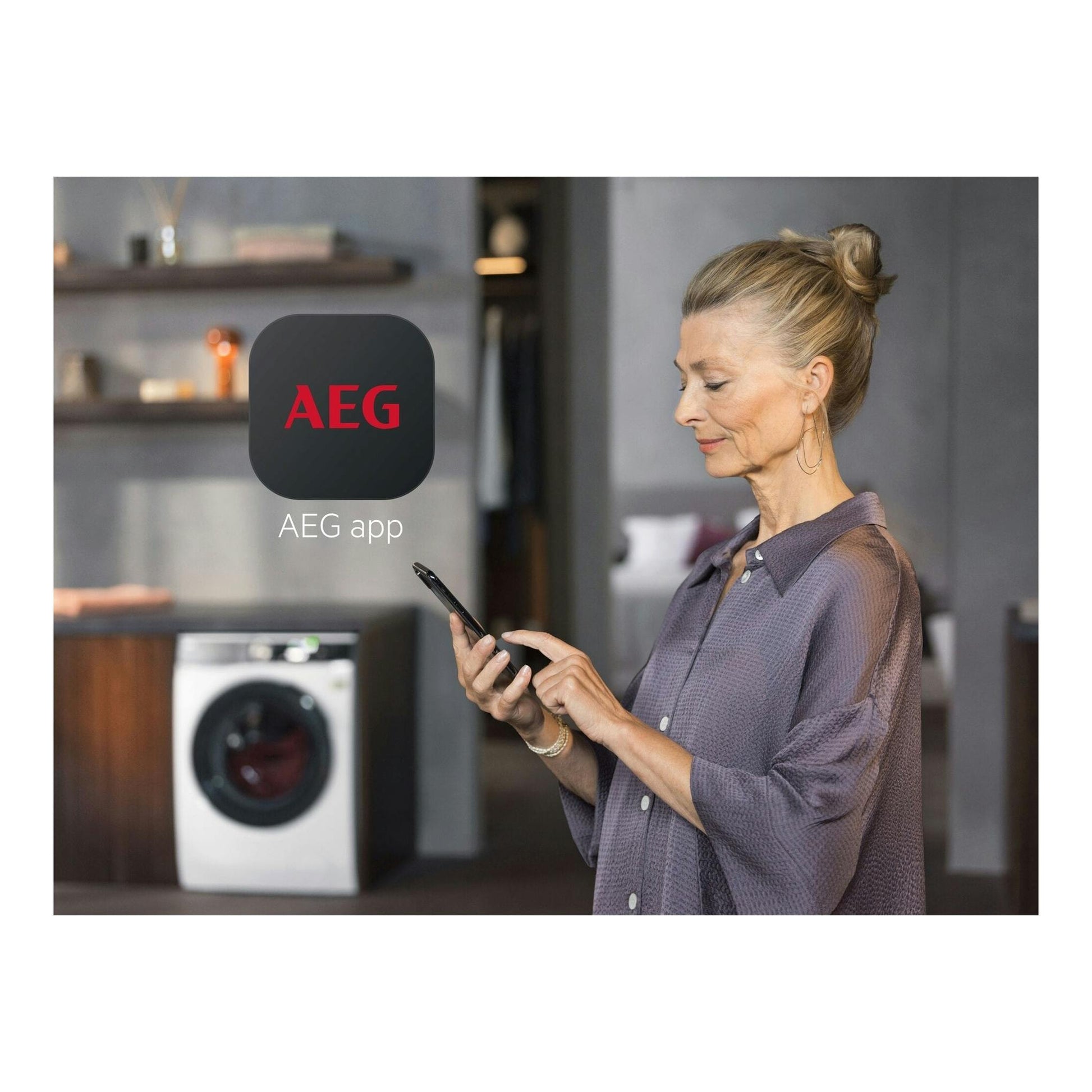 Mujer con móvil frente a una secadora AEG blanca; en pantalla se ve el icono de la app AEG.