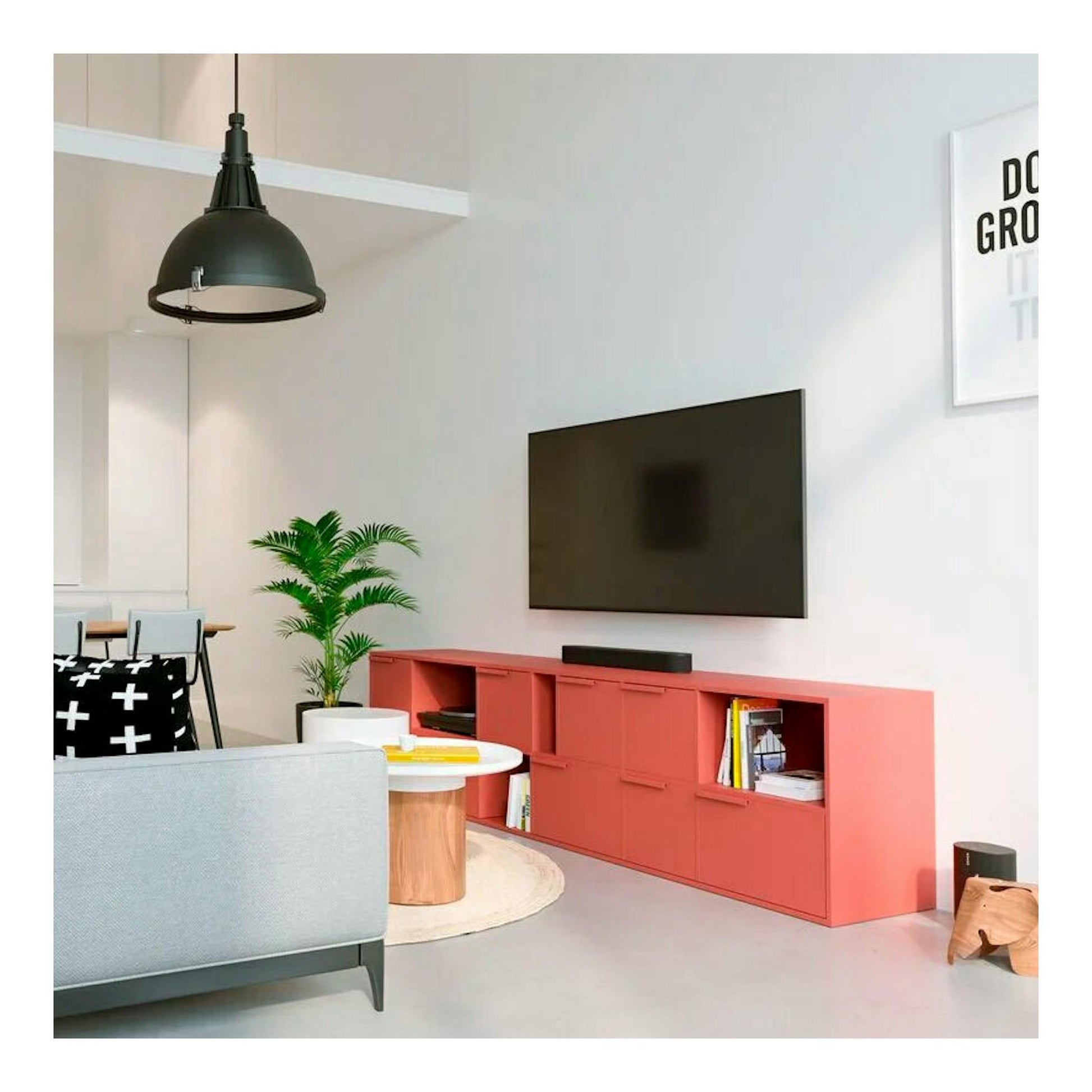 Soporte TV Vogels MA3000, vista frontal, televisor negro en pared sobre mueble coral.